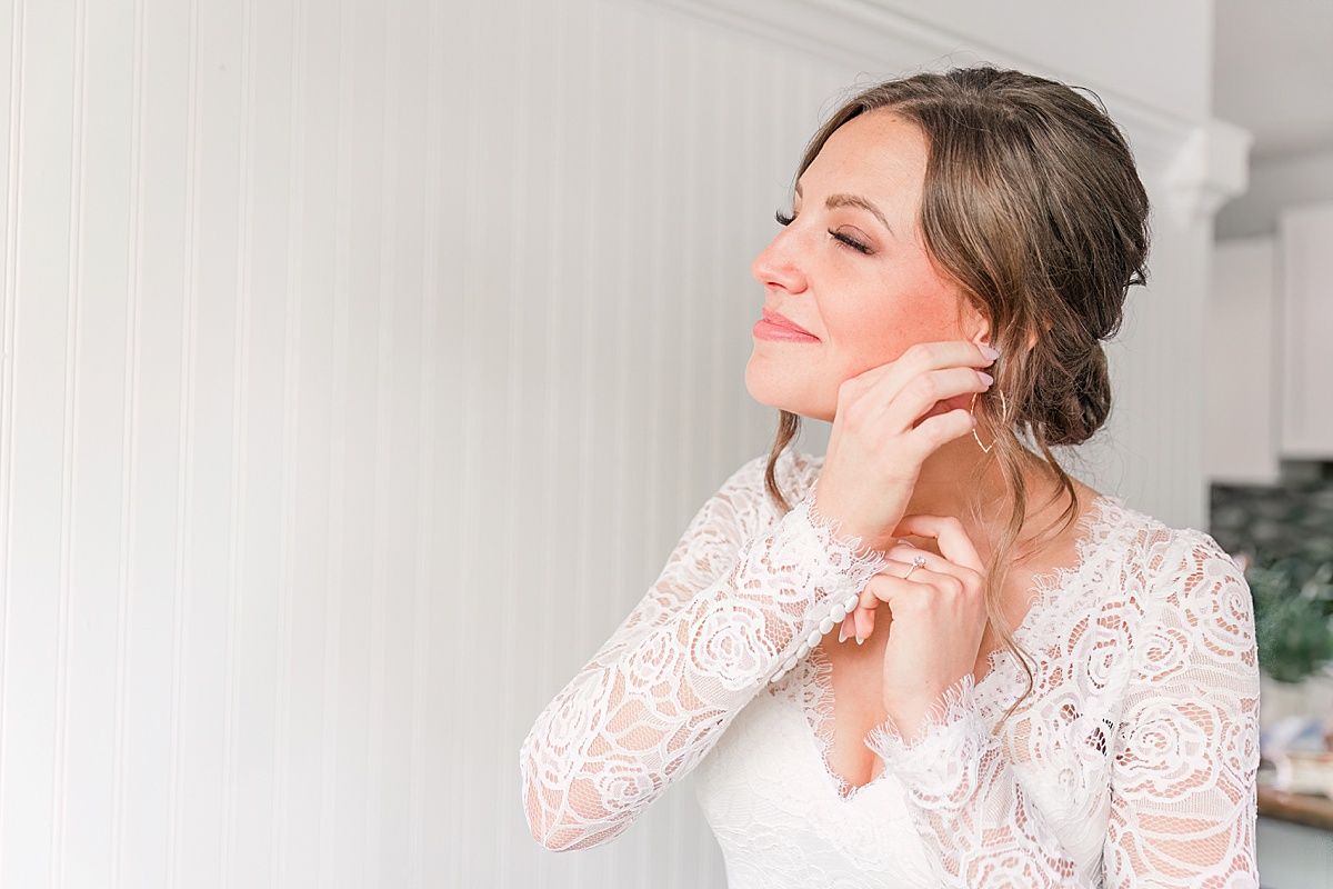 Bride putting on earrings in bridal suite