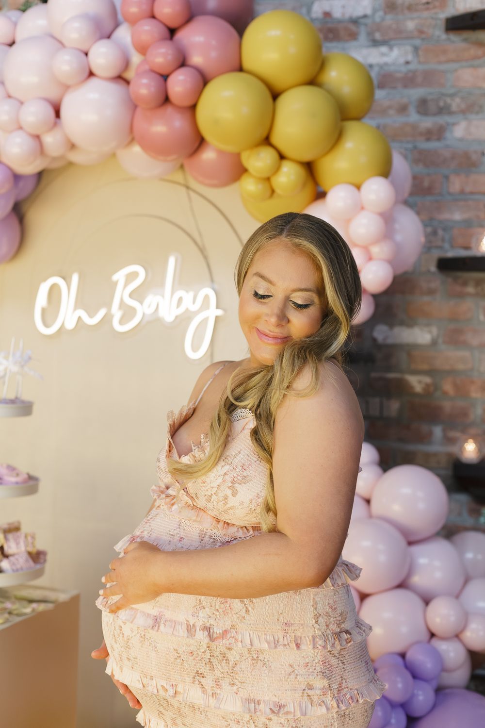 Radiant mom-to-be posing against the backdrop of the stylish decor at her baby shower, photographed by Paula Ortiz