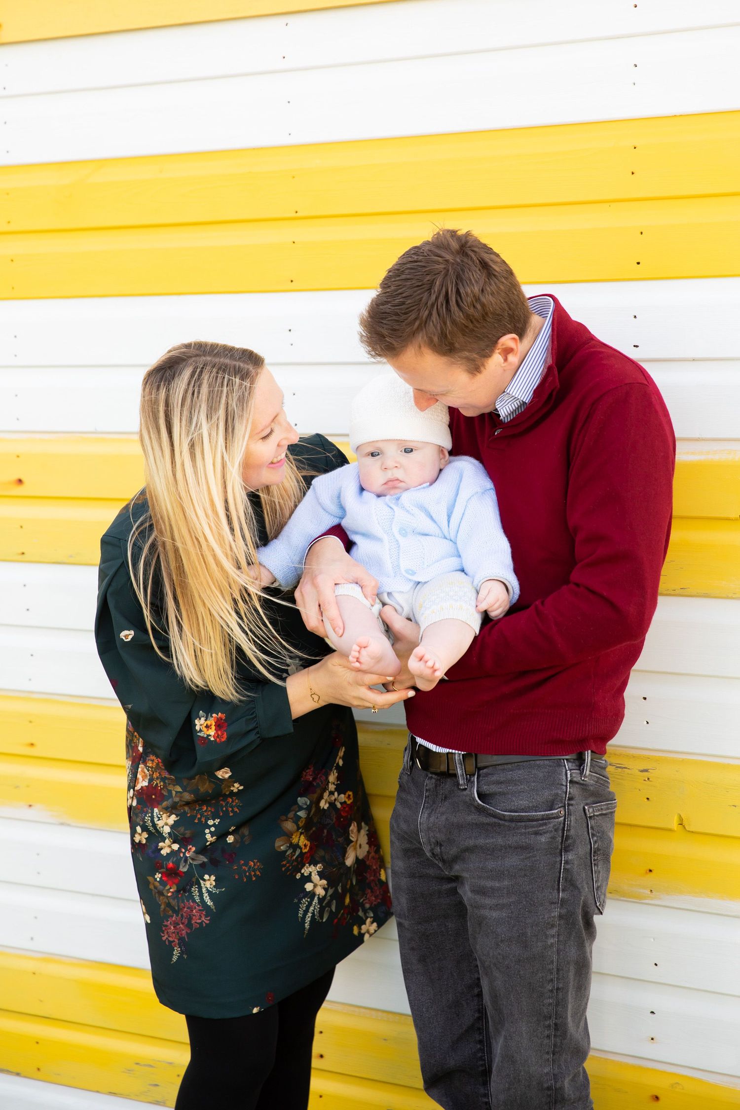 Family poses together against yellow and white striped wall background.
