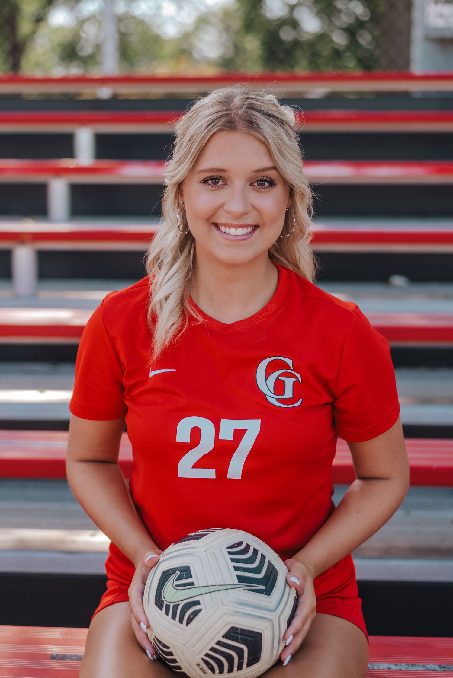 soccer player holding a ball, smiling in the bleachers