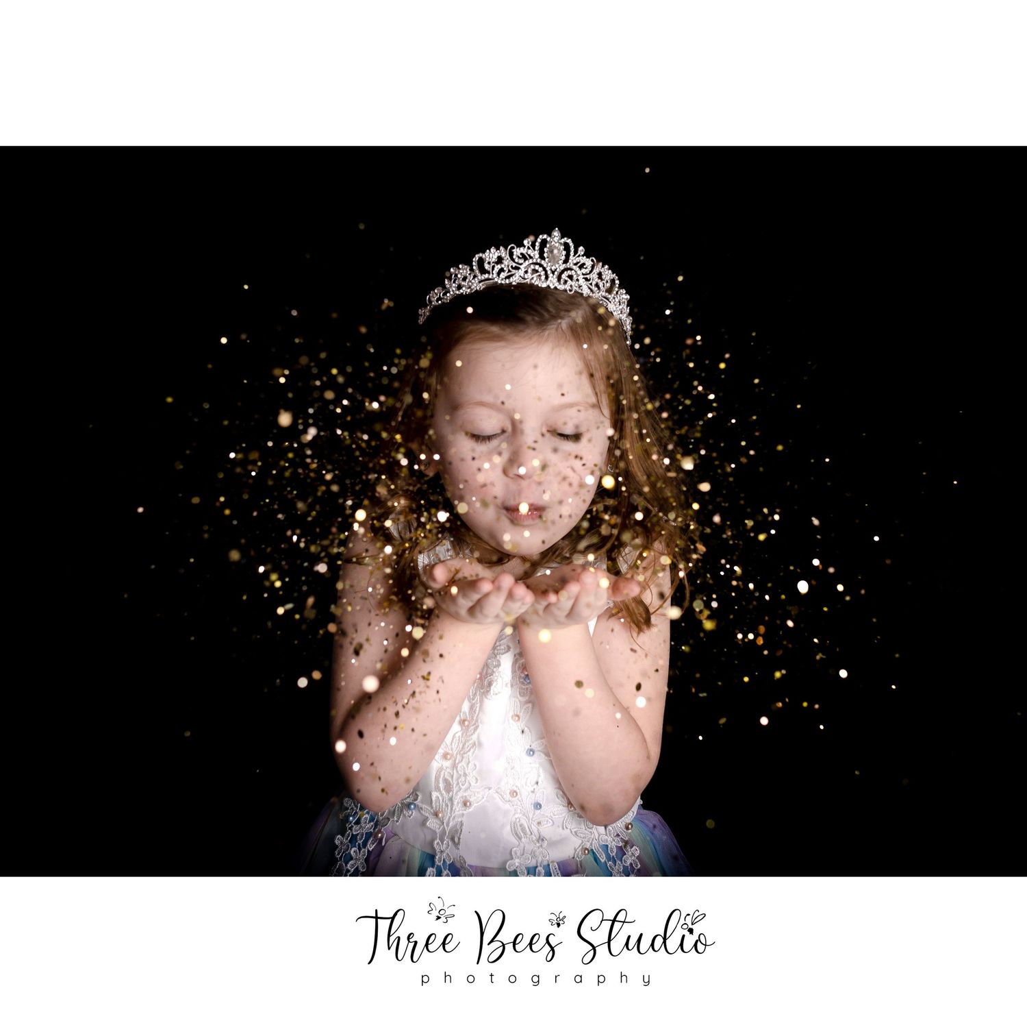 Whimsical photo with glitter being blown into the air against black backdrop.