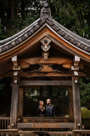 Traditional Japanese wooden gate structure with ornate roof details in garden setting.