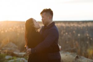 A couple embraces against a scenic mountain backdrop during golden hour.