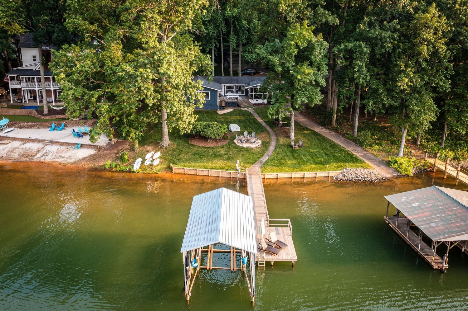 Aerial view of lakefront properties with private docks and boats along a wooded shoreline.
