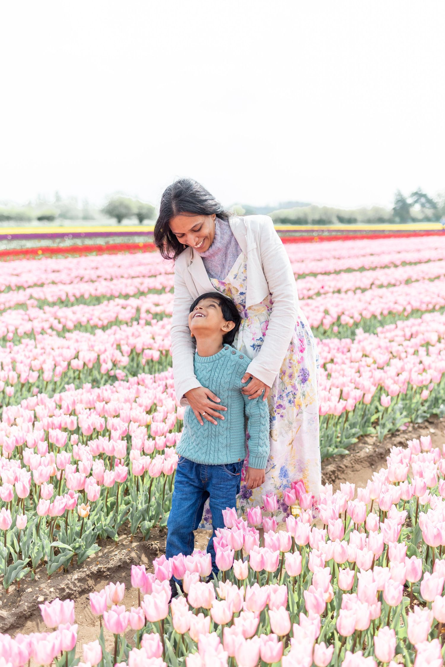 Parent and child sharing a joyful moment together in a blooming tulip field.