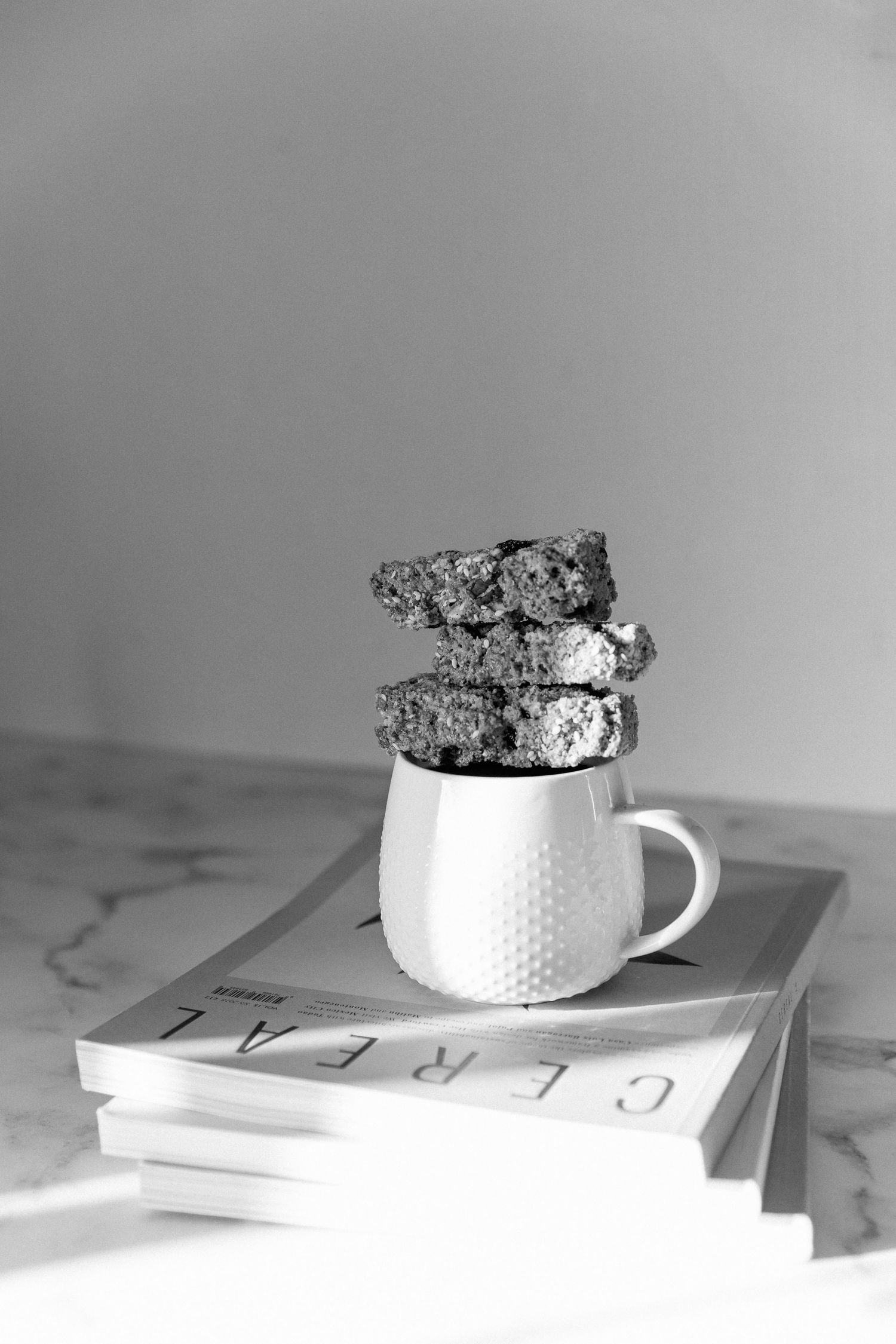 A steaming cup of THIRTEEN Coffee Company coffee with a homemade rusk.Stacked on a pile of Cereal Magazines.