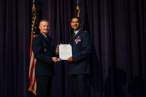 Military officers exchanging documents during an awards ceremony.