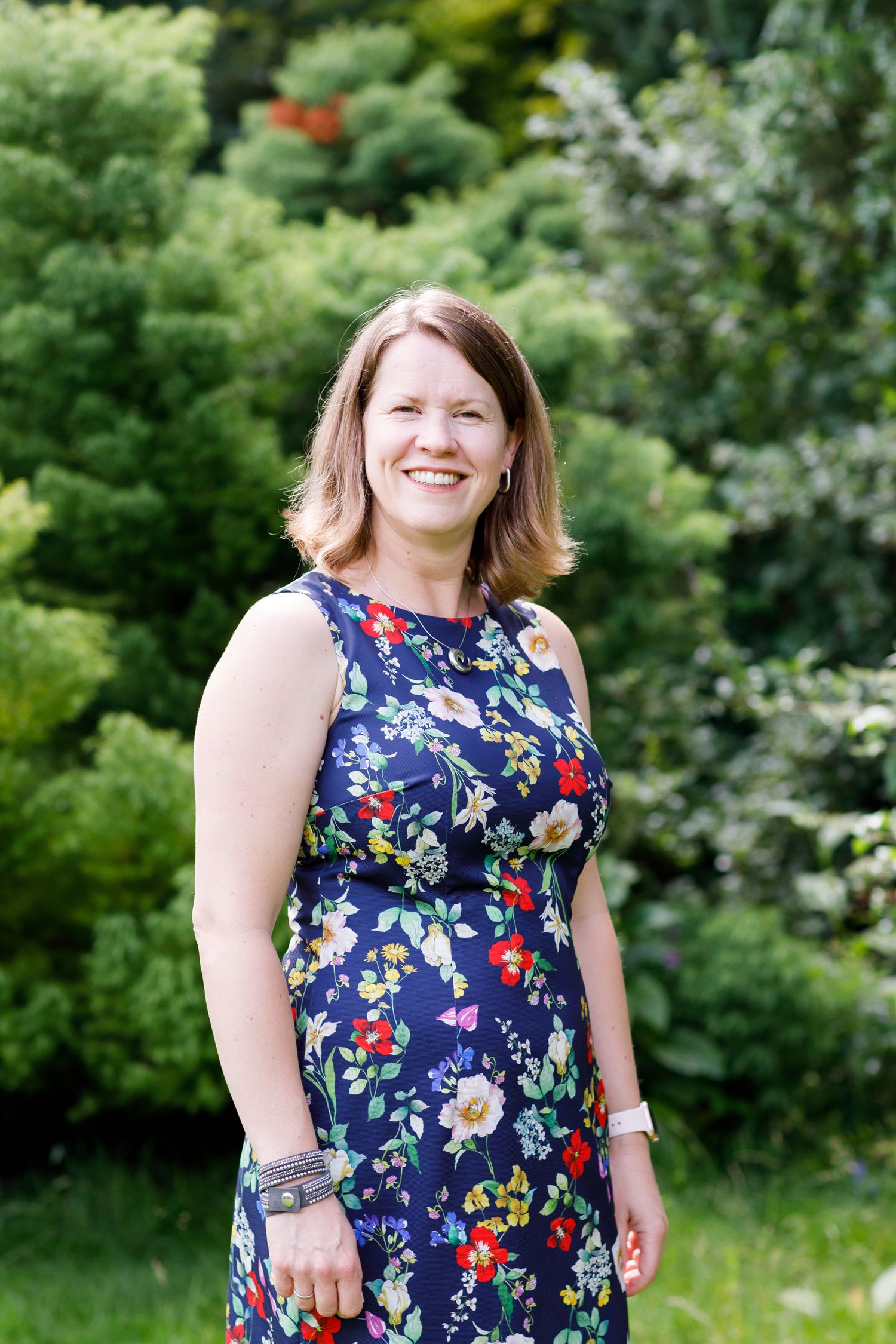 Outdoor portrait showing floral dress against lush green garden background during business branding photoshoot.