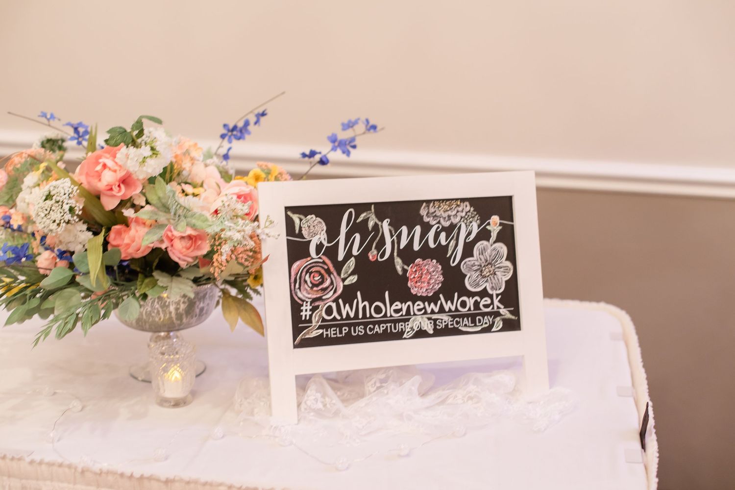 Elegant wedding reception table setting with white linens, chalkboard signs and peach floral centerpieces.