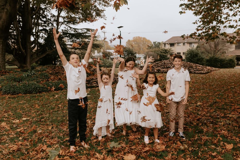 Family enjoying playful time together in a fall setting with scattered leaves.