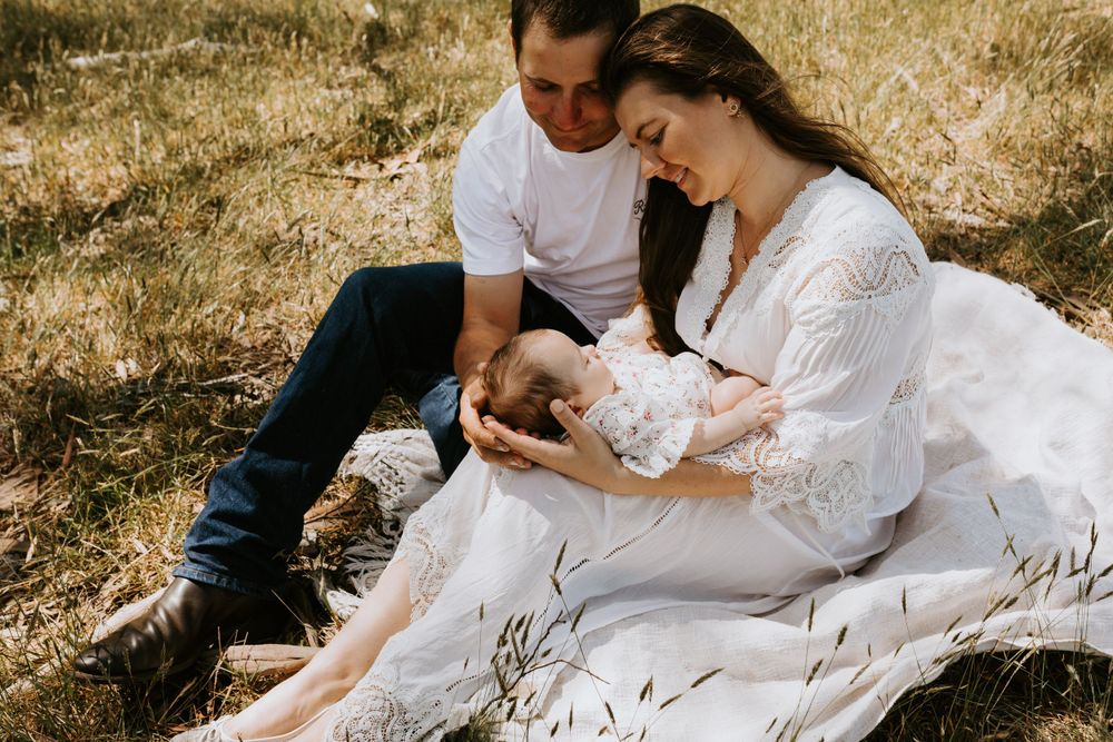 Family sitting together in rustic field during golden hour photoshoot.