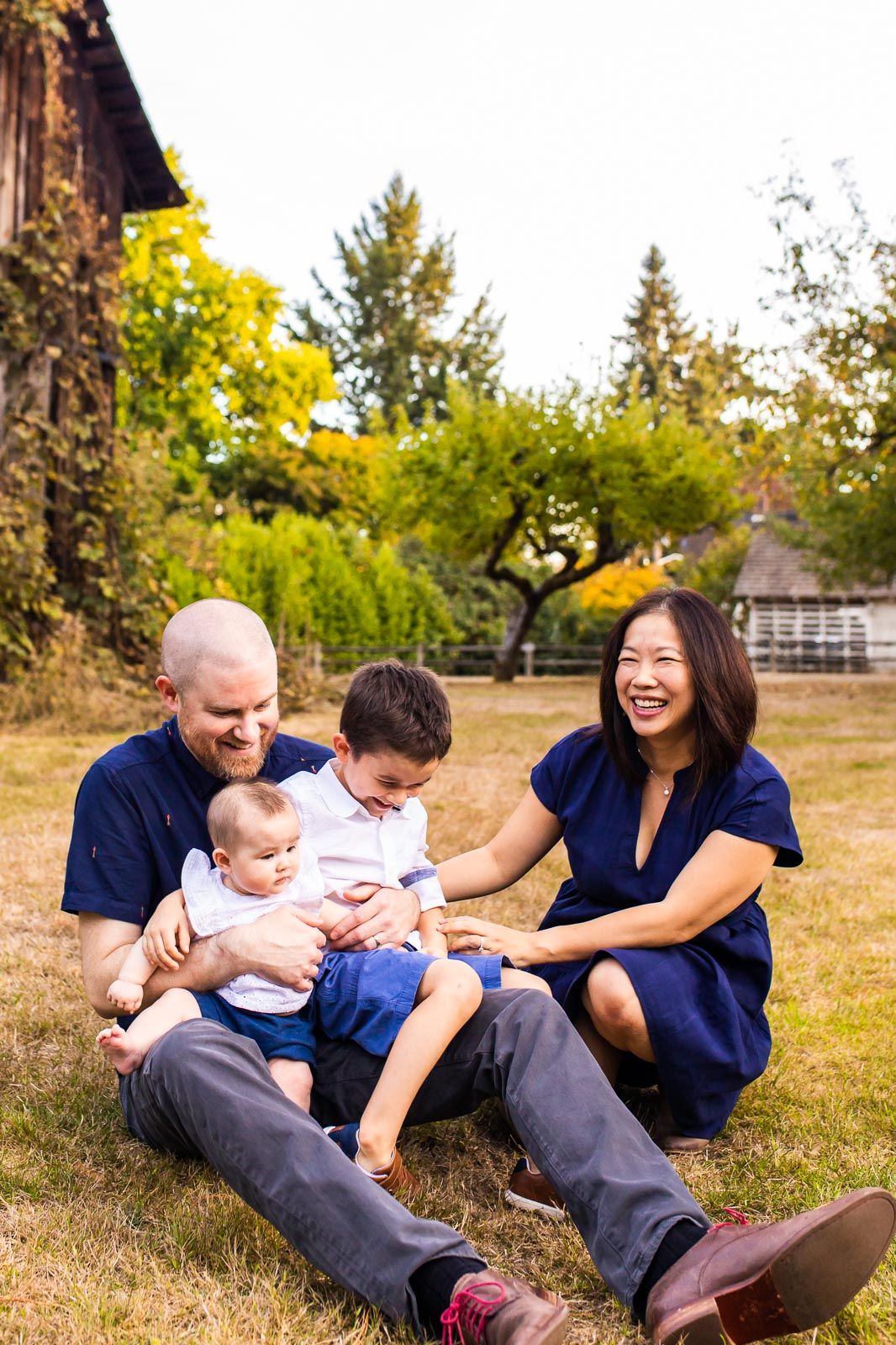 Kirkland family photographer captures family laughing together in front of a barn
