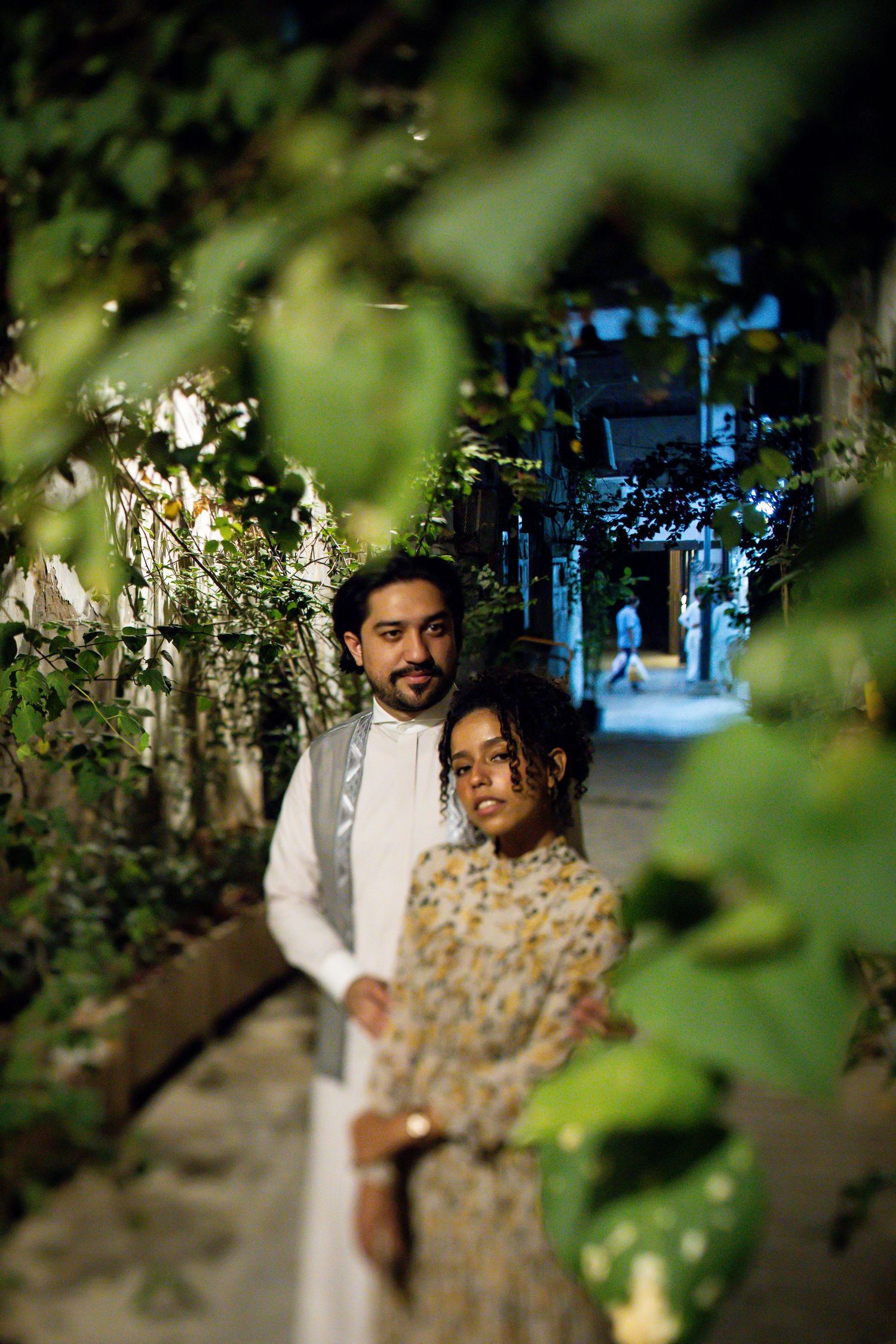 Couple poses for a romantic portrait among lush garden foliage and archways.