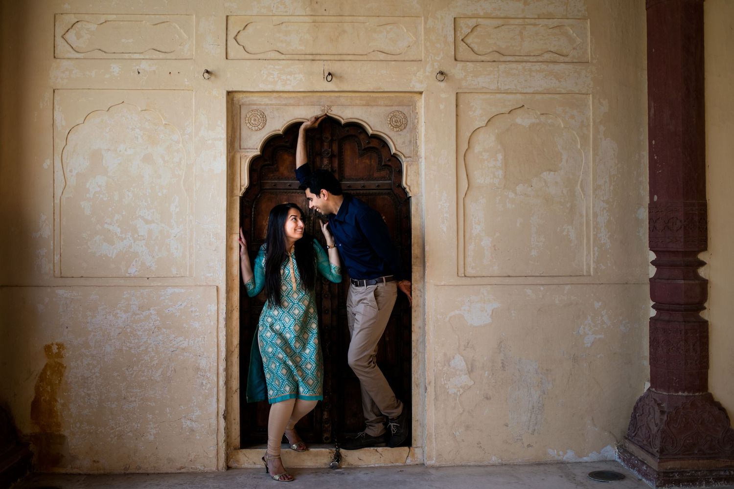 A playful moment between two people framed within an ornate archway.
