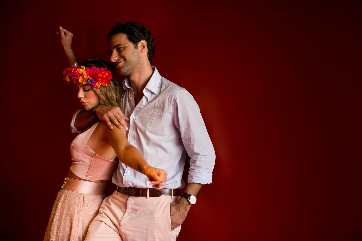 Dancing couple in formal attire against red backdrop with dramatic lighting.