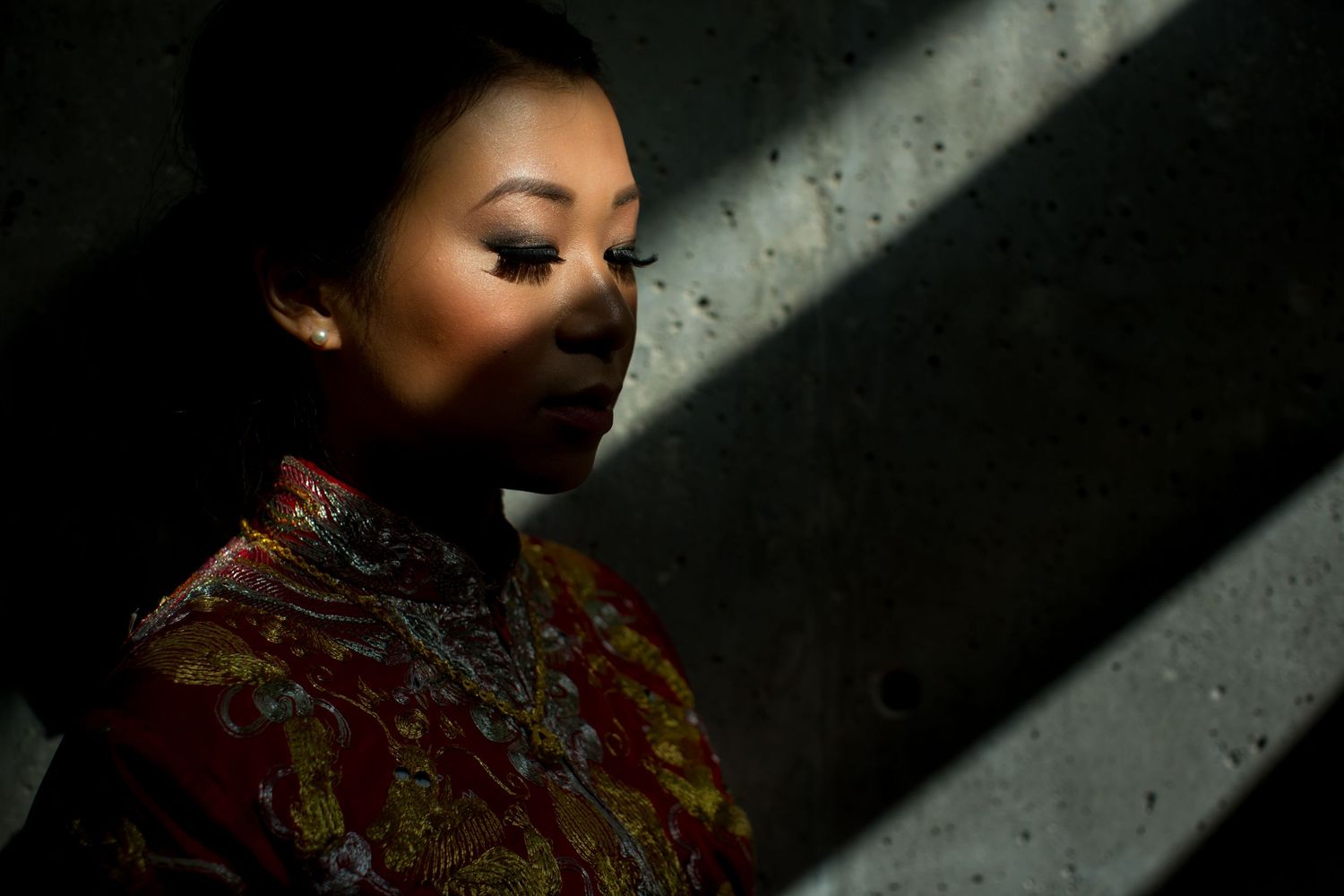 Portrait of woman in traditional dress with dramatic side lighting creating artistic shadows.