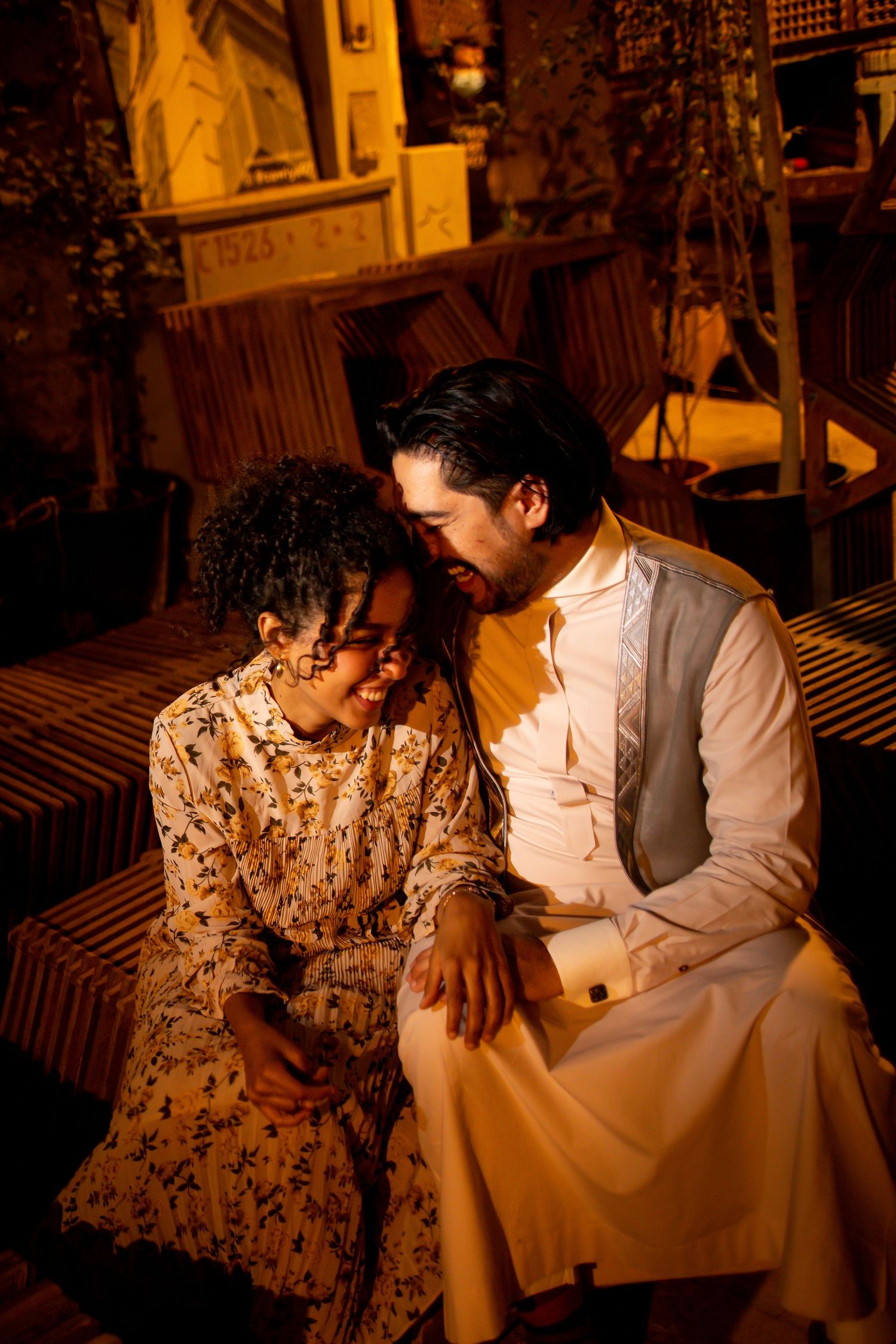 A romantic couple shares an intimate moment in warm lighting on a wooden bench.