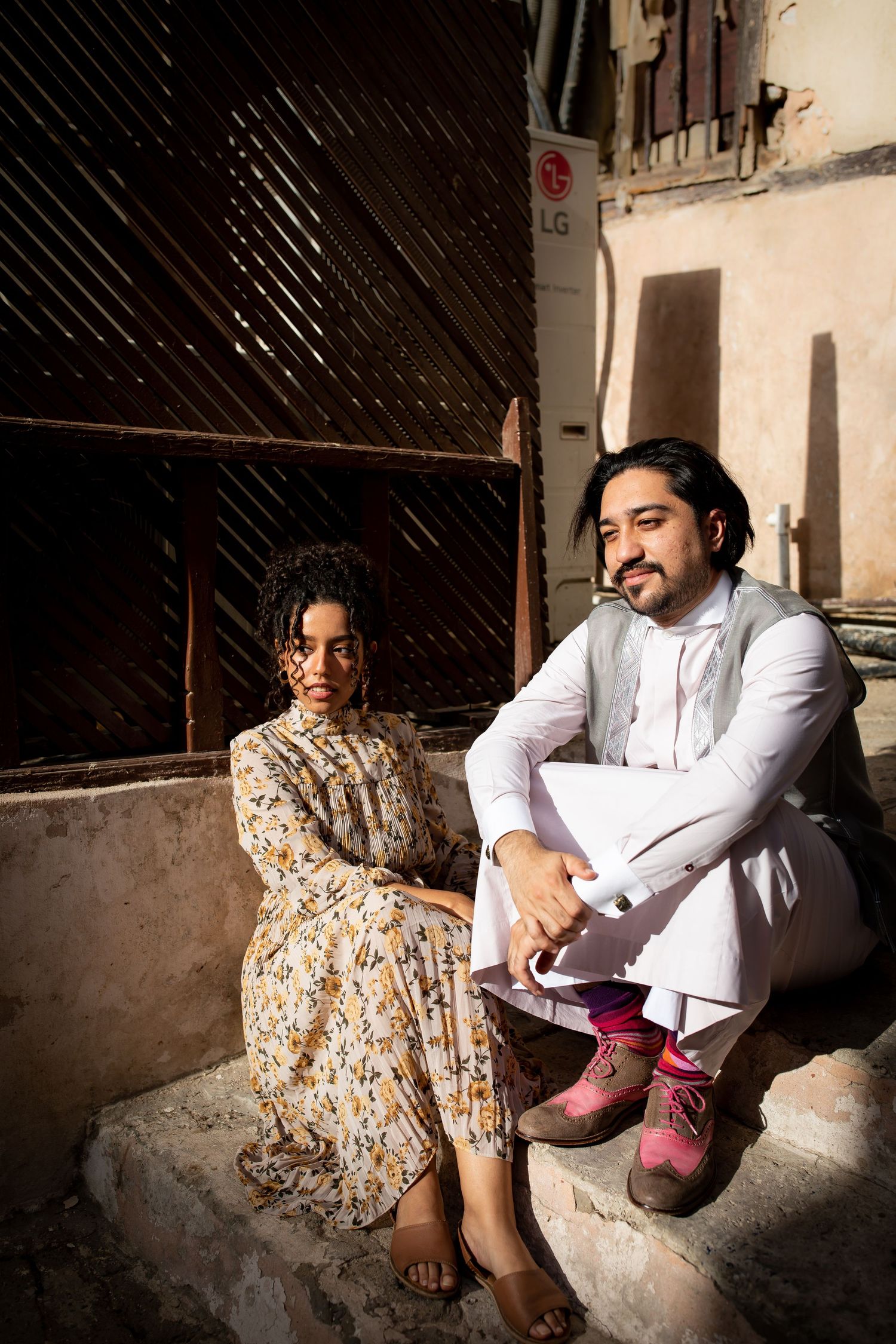 Casual portrait on stone steps with vintage floral dress and traditional white attire.
