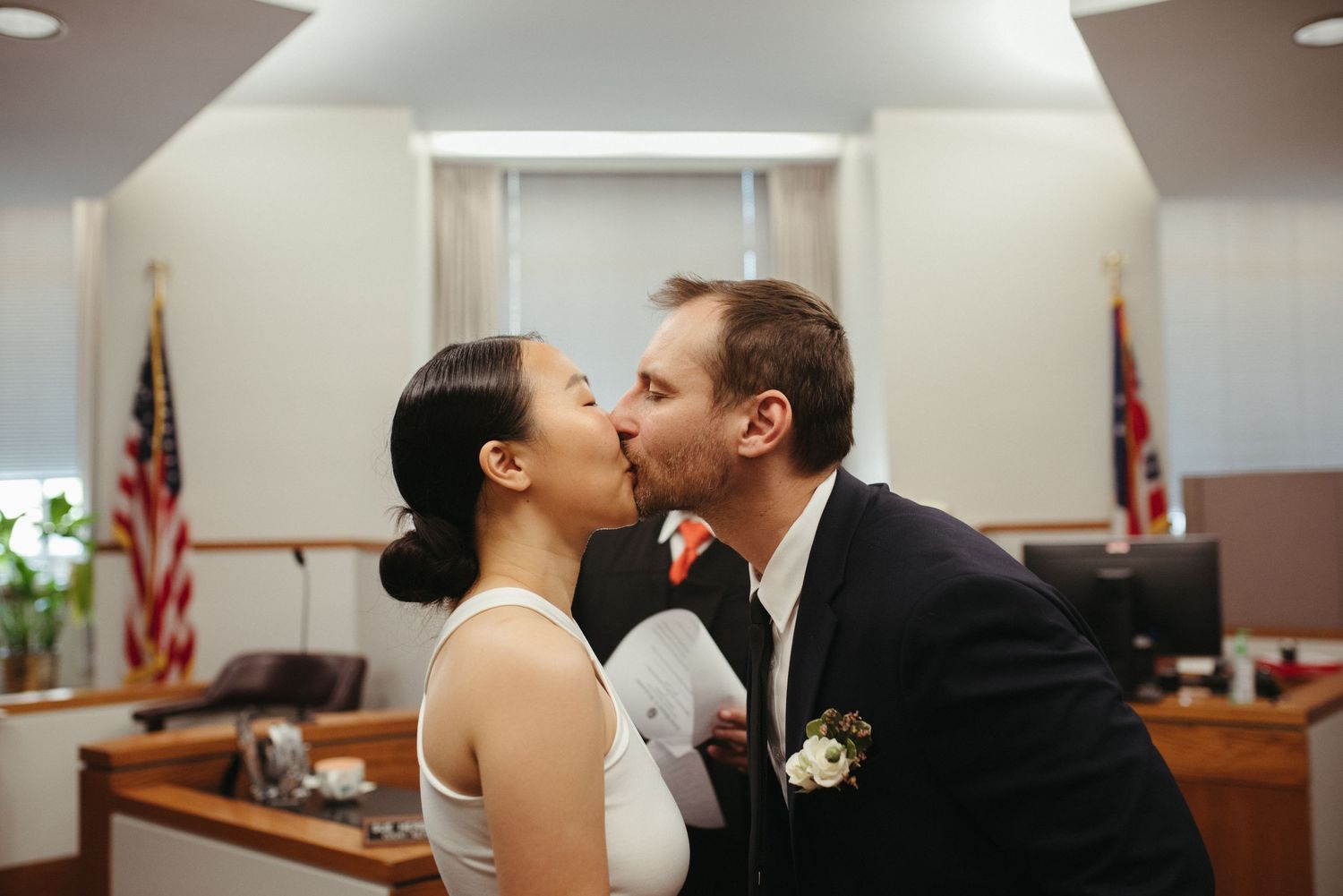 A tender kiss between newlyweds during their courthouse ceremony.