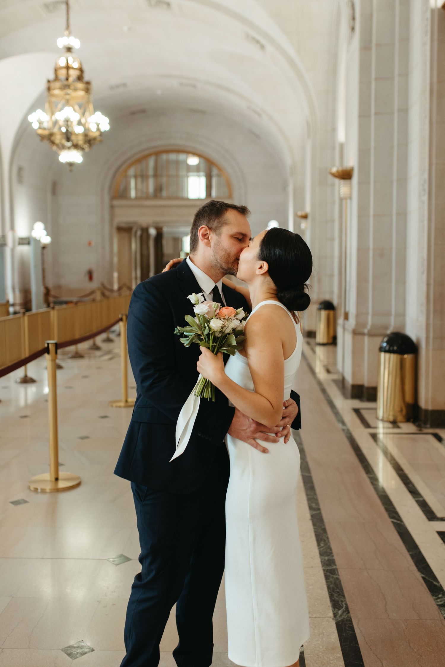 A romantic moment between newlyweds in an ornate hallway with vaulted ceilings.