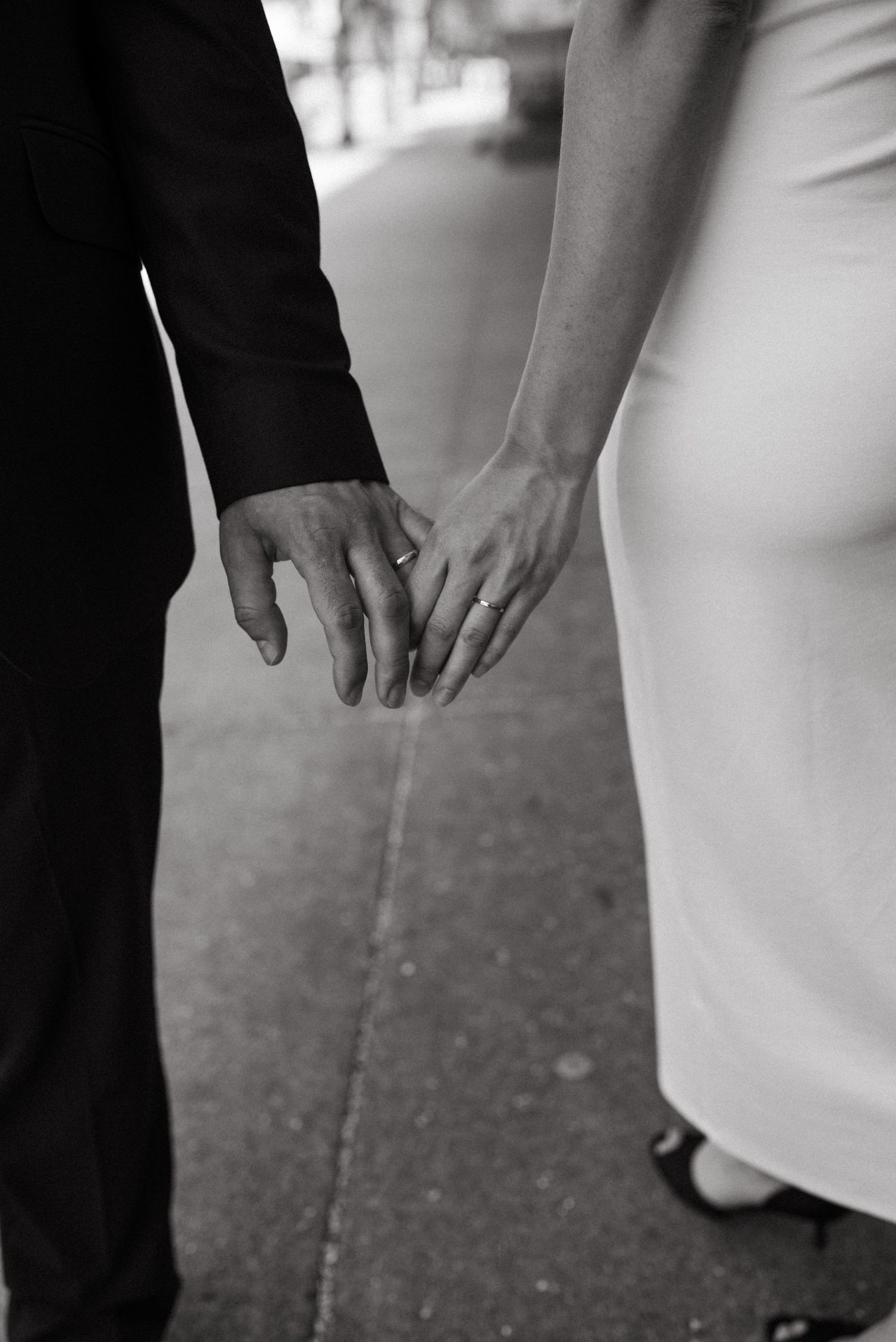 Close-up black and white photo of newlyweds' hands touching tenderly.