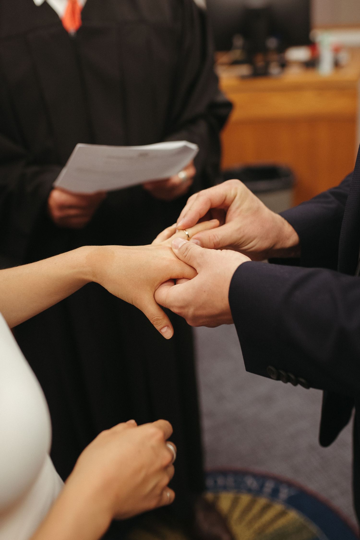 Close-up of hands during a wedding ring exchange ceremony.