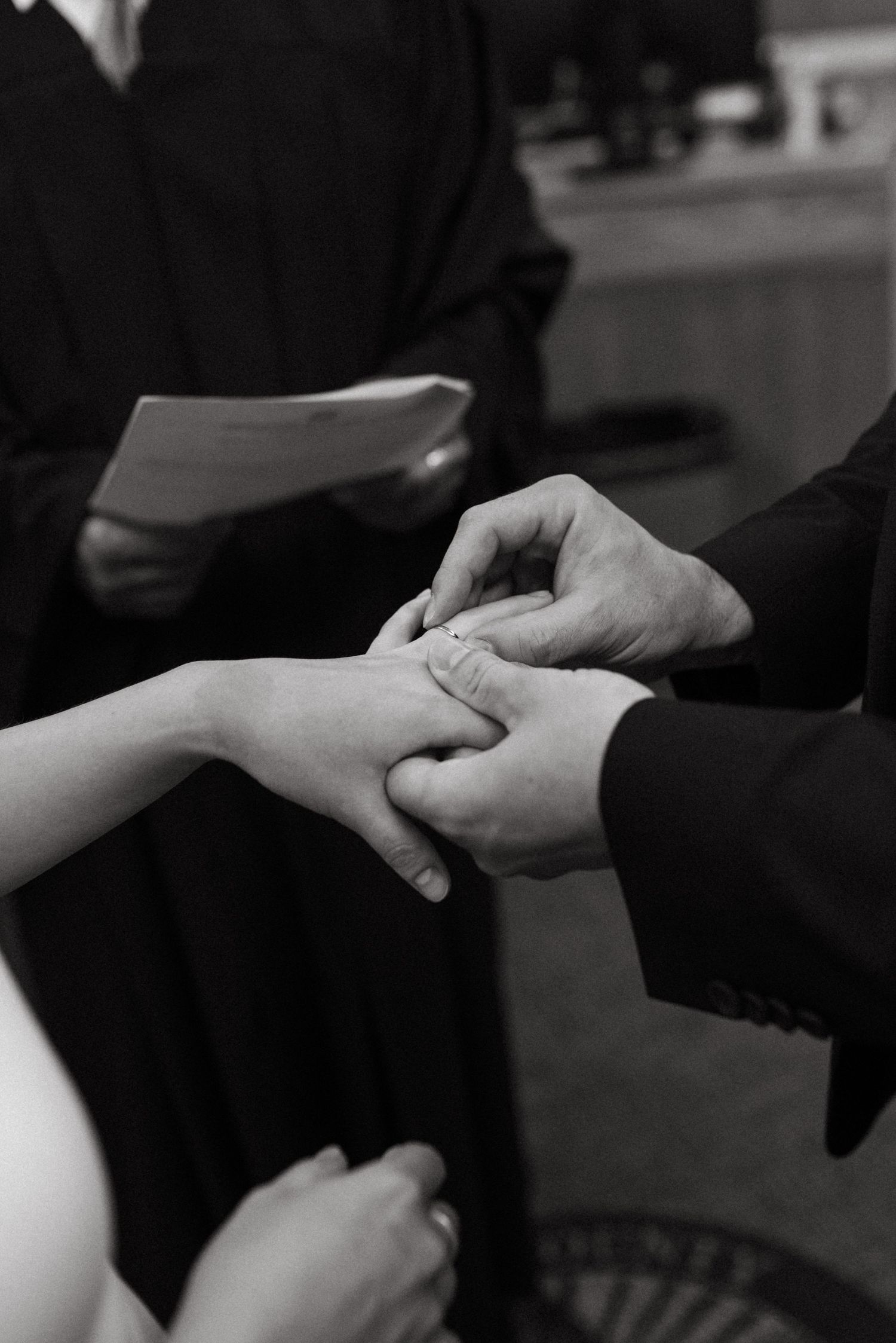 Black and white photo of wedding ring exchange during ceremony.