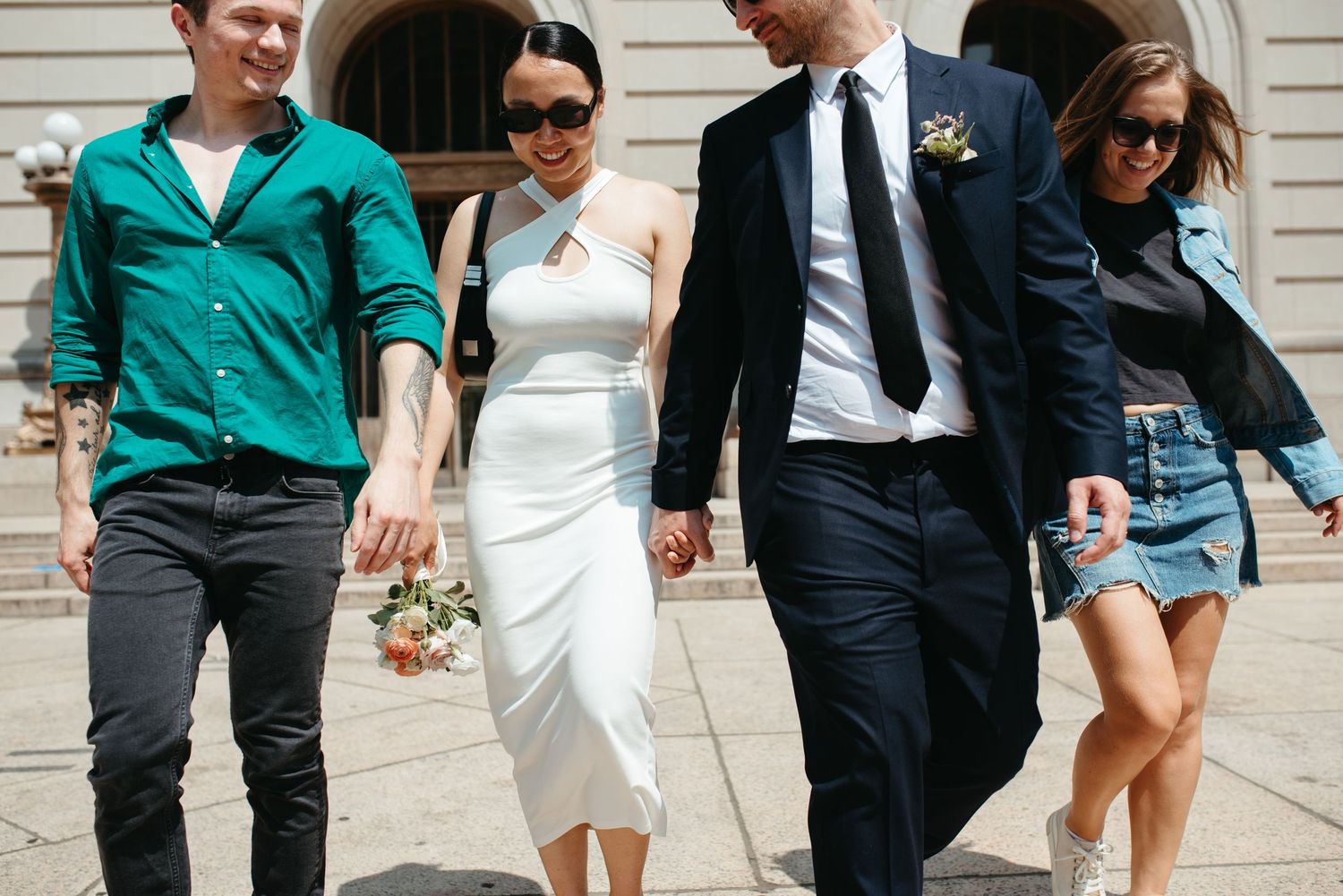 Group of friends walk together in casual and formal attire outside historic building.