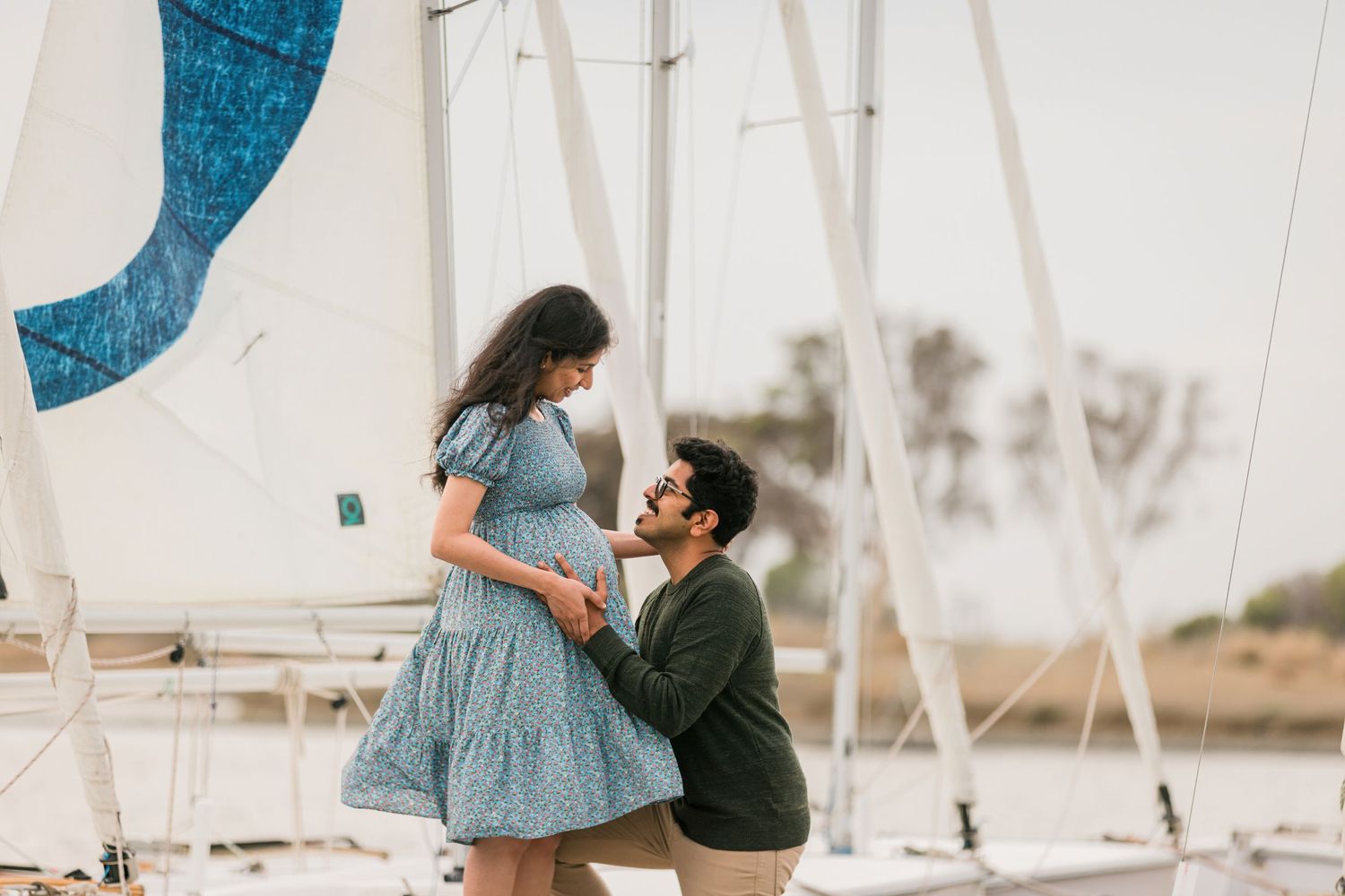 A romantic proposal moment on a dock with sailboats in the background.