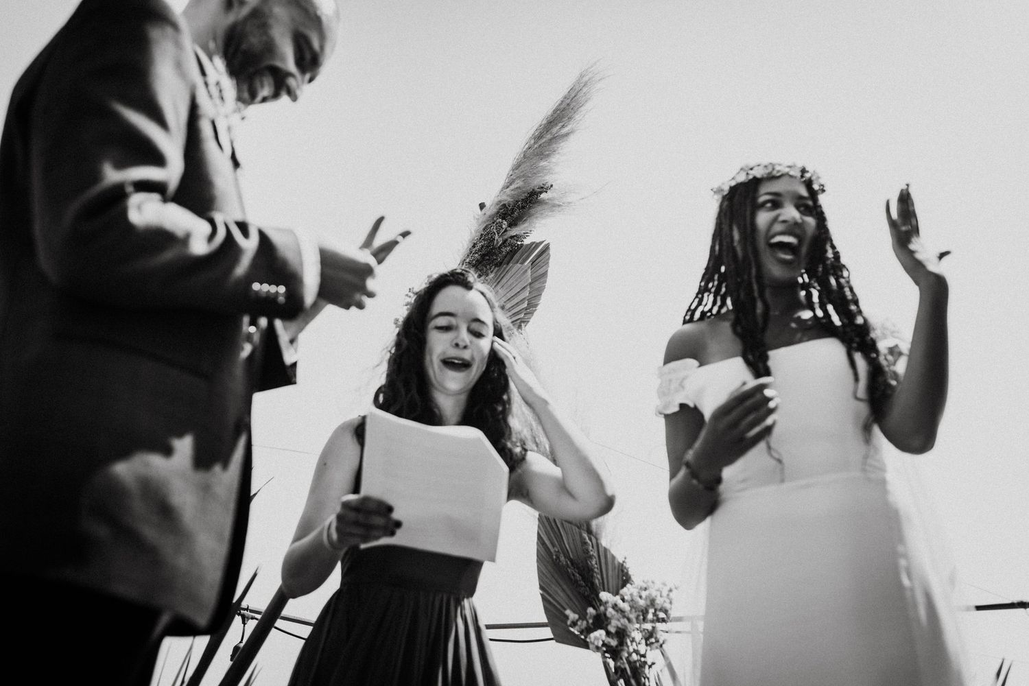 Black and white photo of guests laughing and celebrating at an outdoor event.