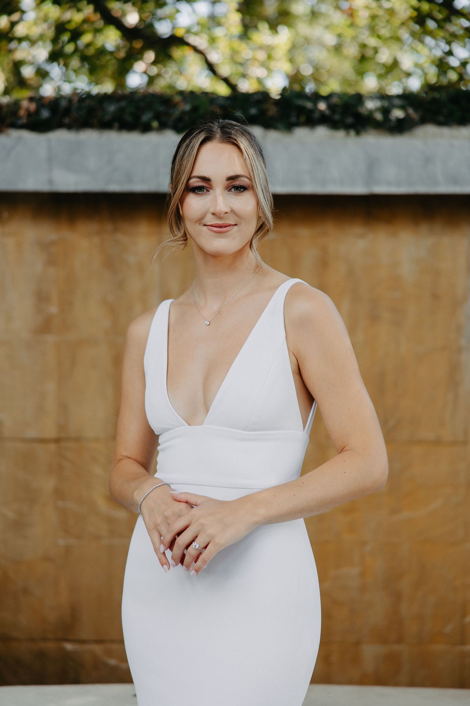 Elegant white wedding dress photographed in an outdoor garden setting.