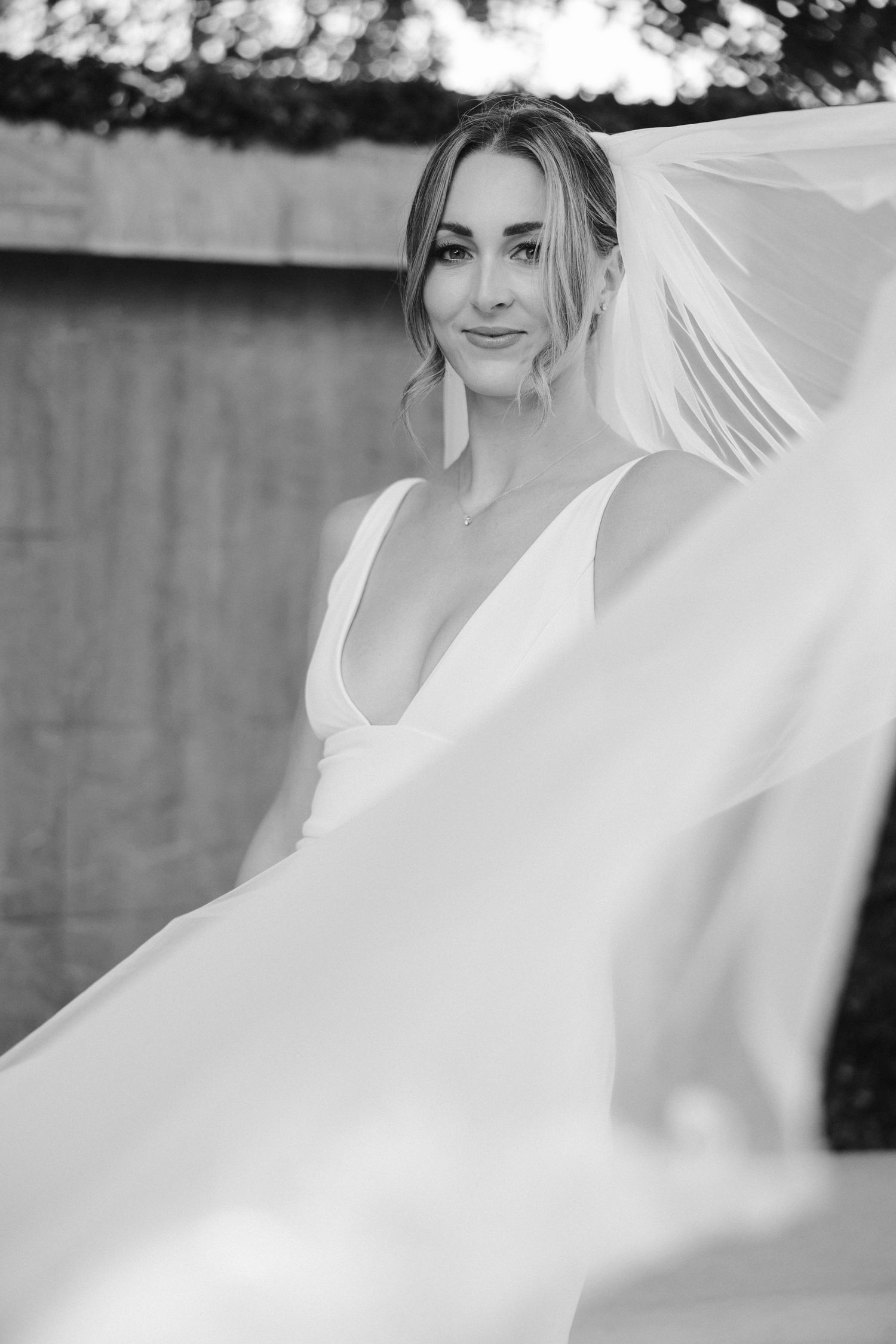 Artistic black and white bridal portrait with flowing veil in natural light.
