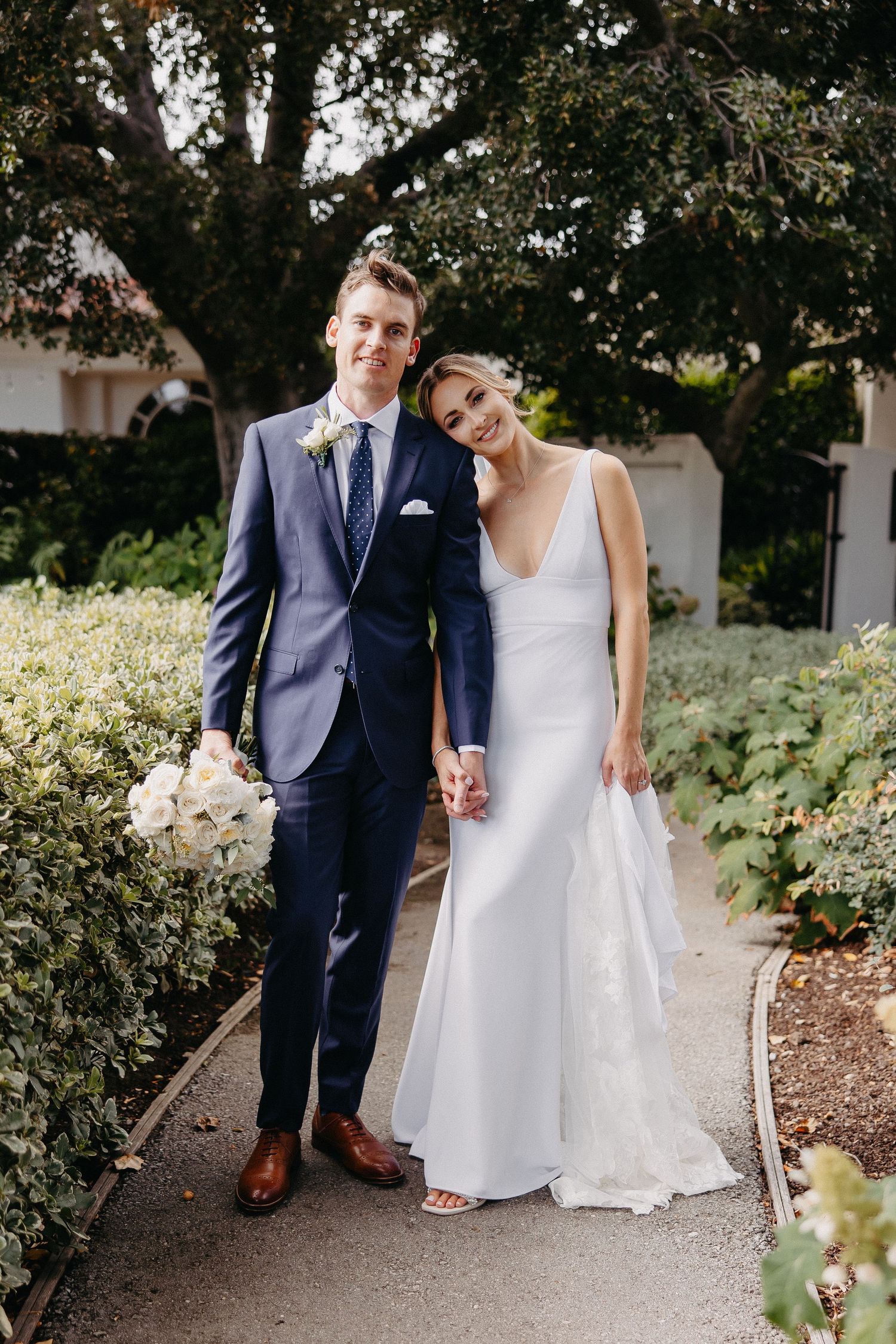 A tender moment between newlyweds as they pose together on a garden walkway.