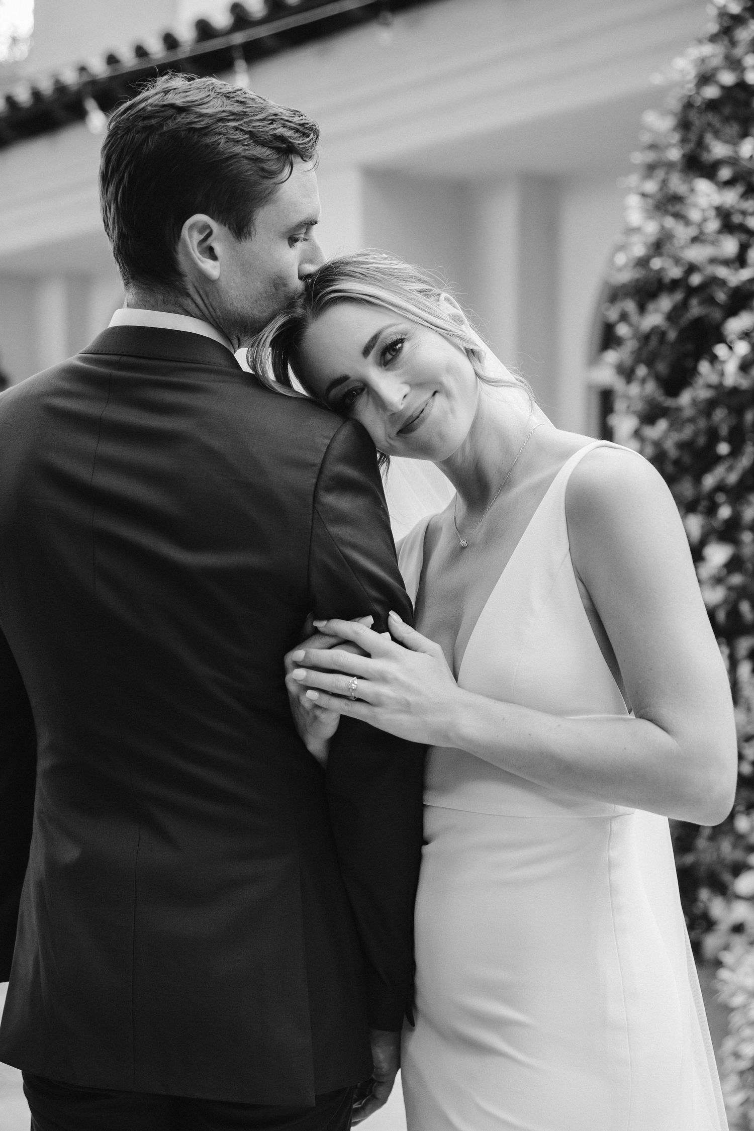 Black and white intimate portrait of newlyweds sharing tender moment in garden.