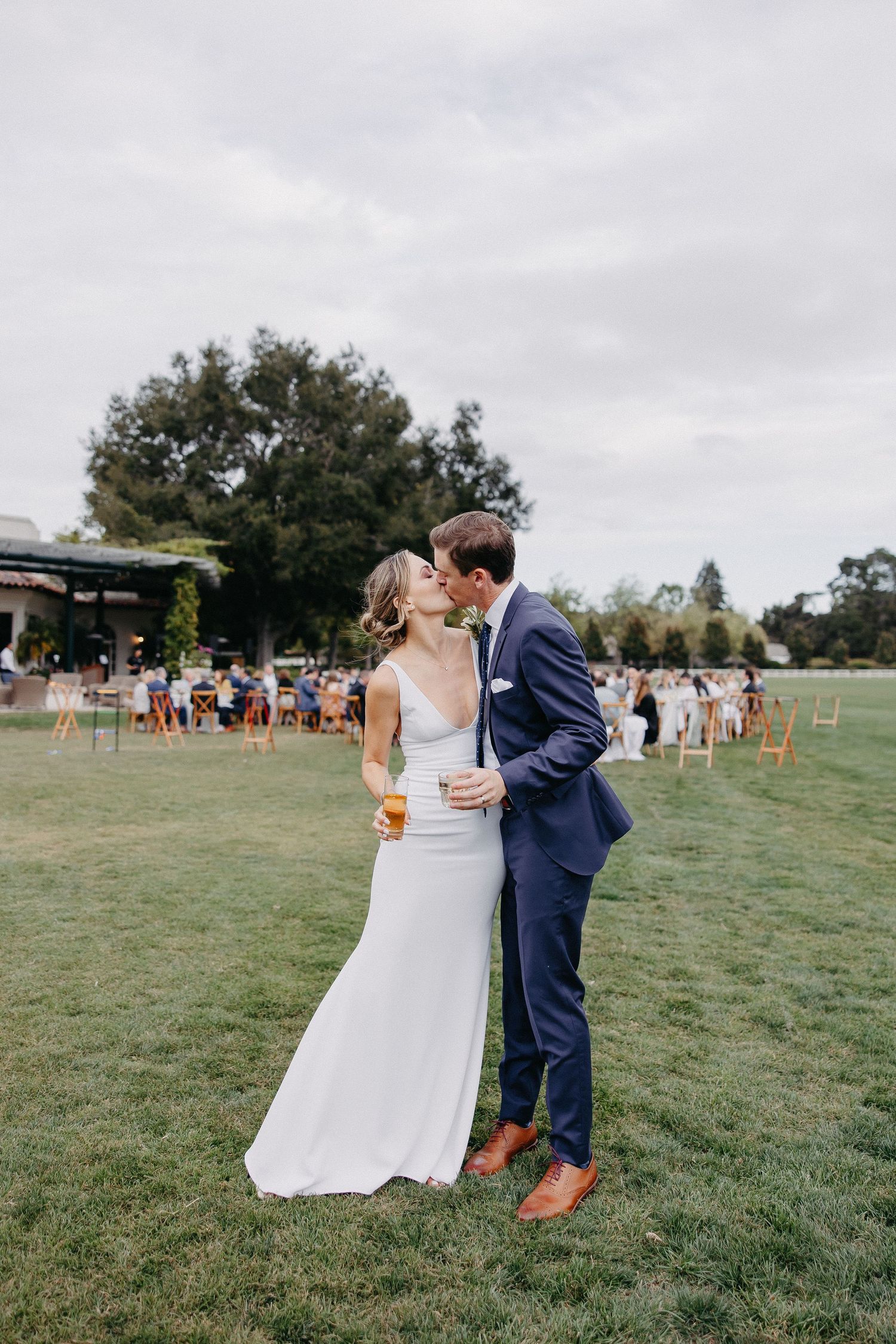 Couple sharing an intimate moment on a grassy lawn during their wedding celebration.