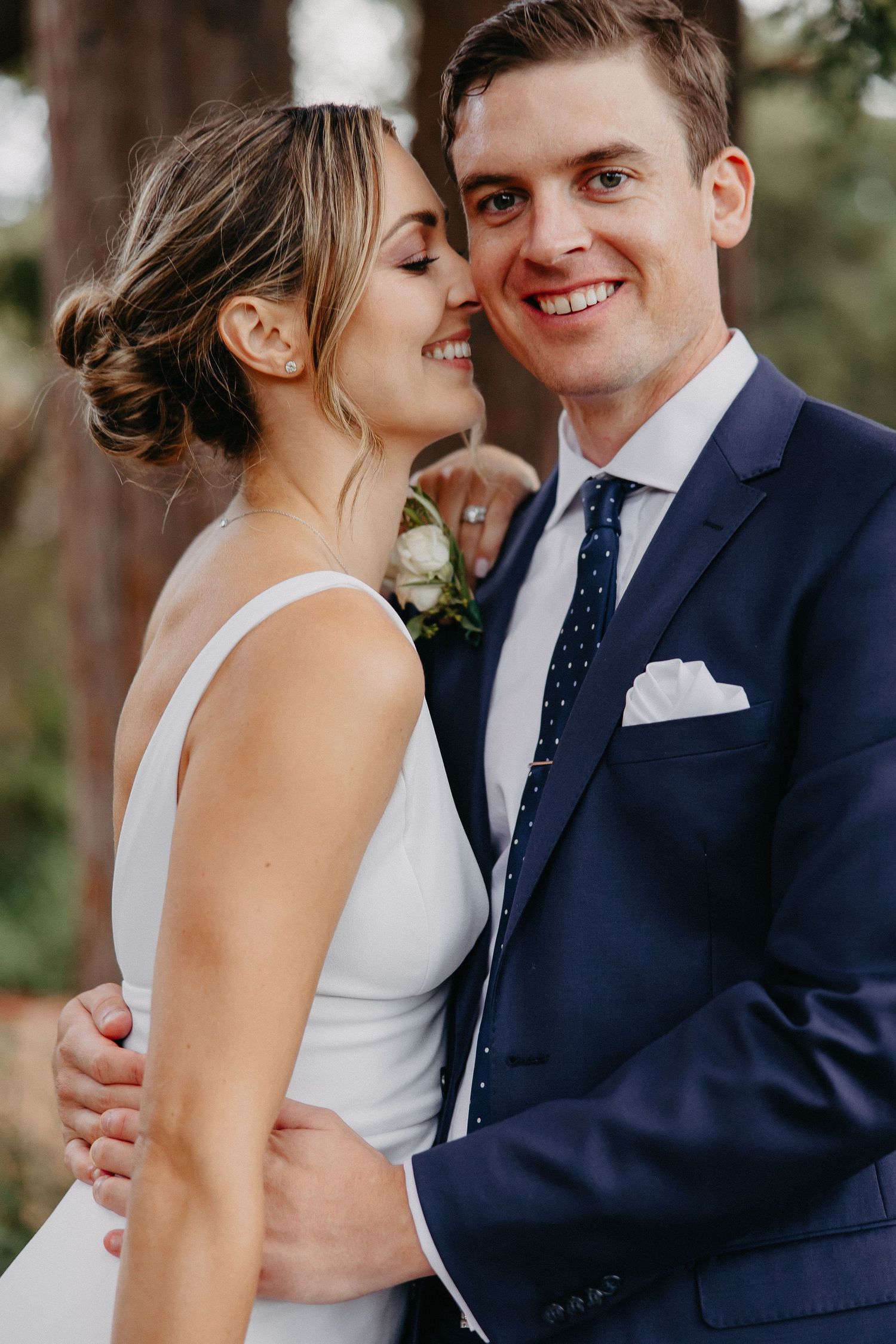Close-up wedding portrait showing tender moment between couple in navy suit and white dress.