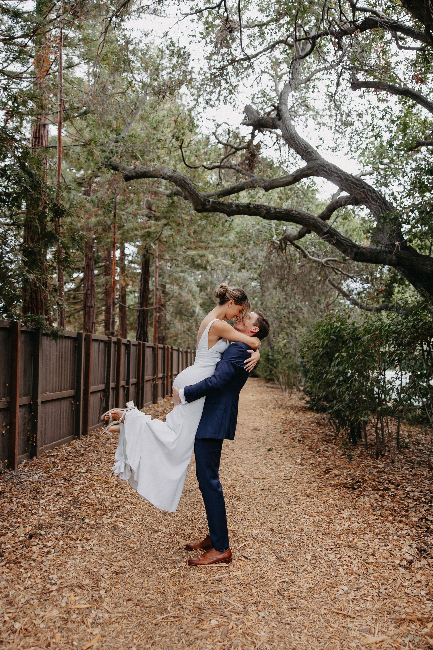 Joyful moment captured on forest path as couple celebrates under twisted oak branches.