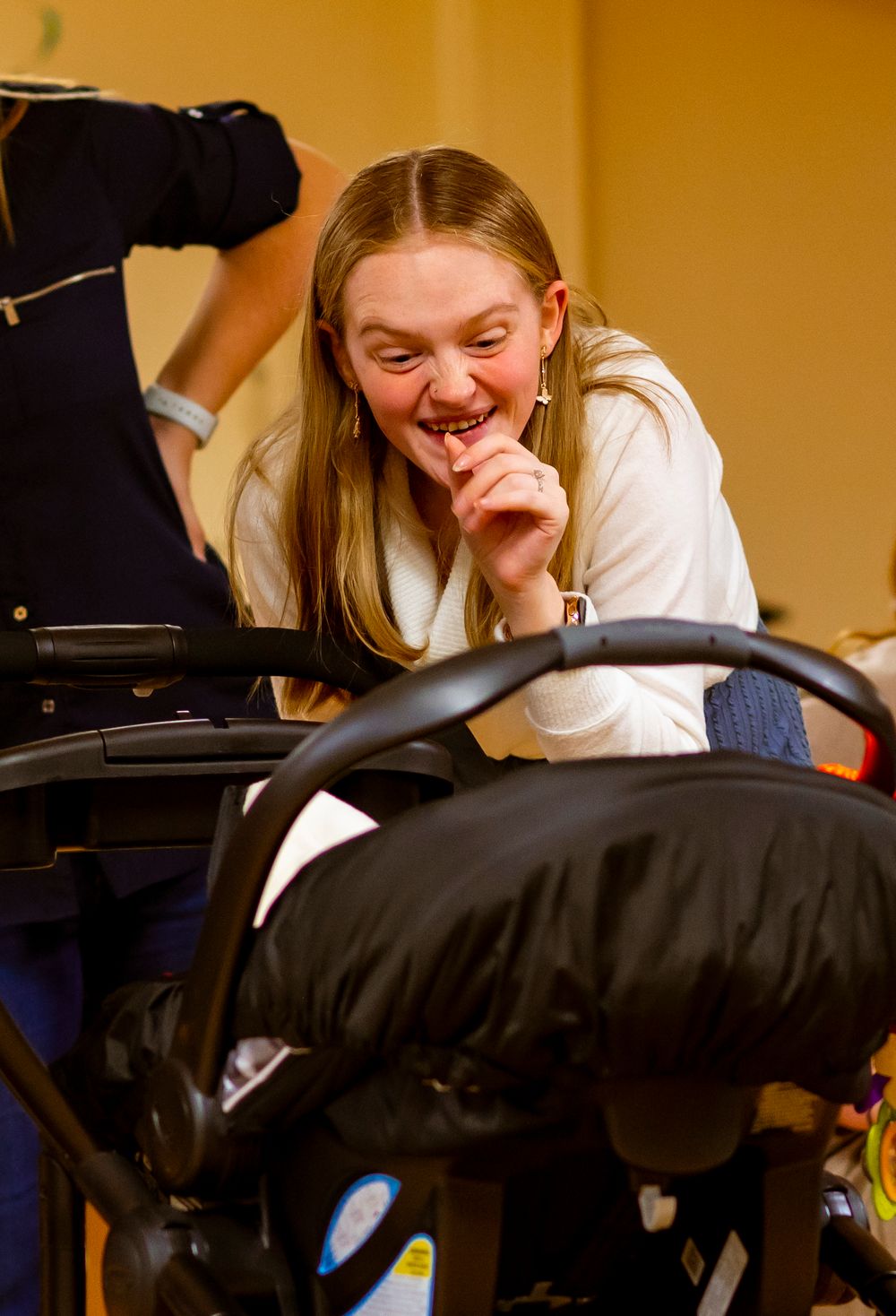 Someone sharing a joyful laugh while seated near a baby carrier.