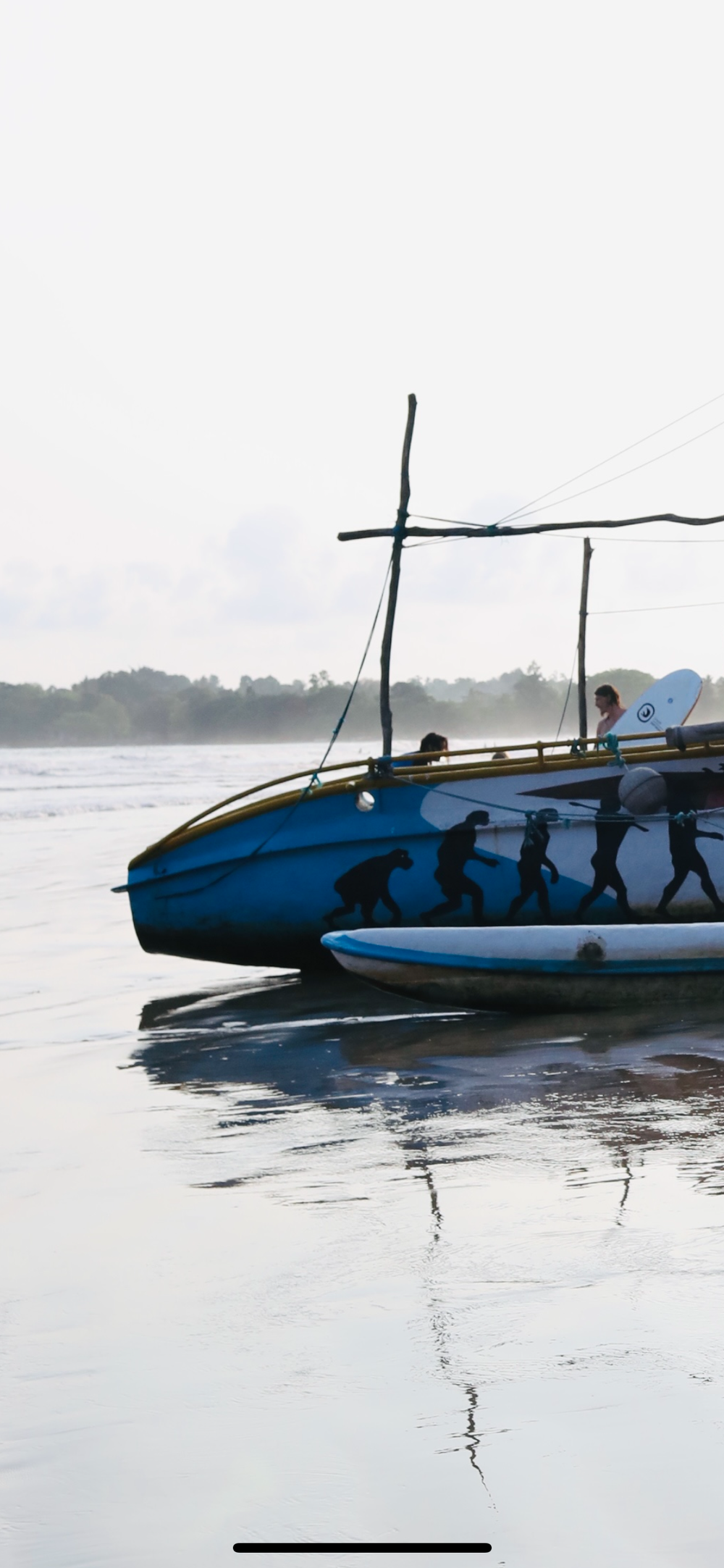 Blue boats on calm water at sunset with silhouettes and reflections.