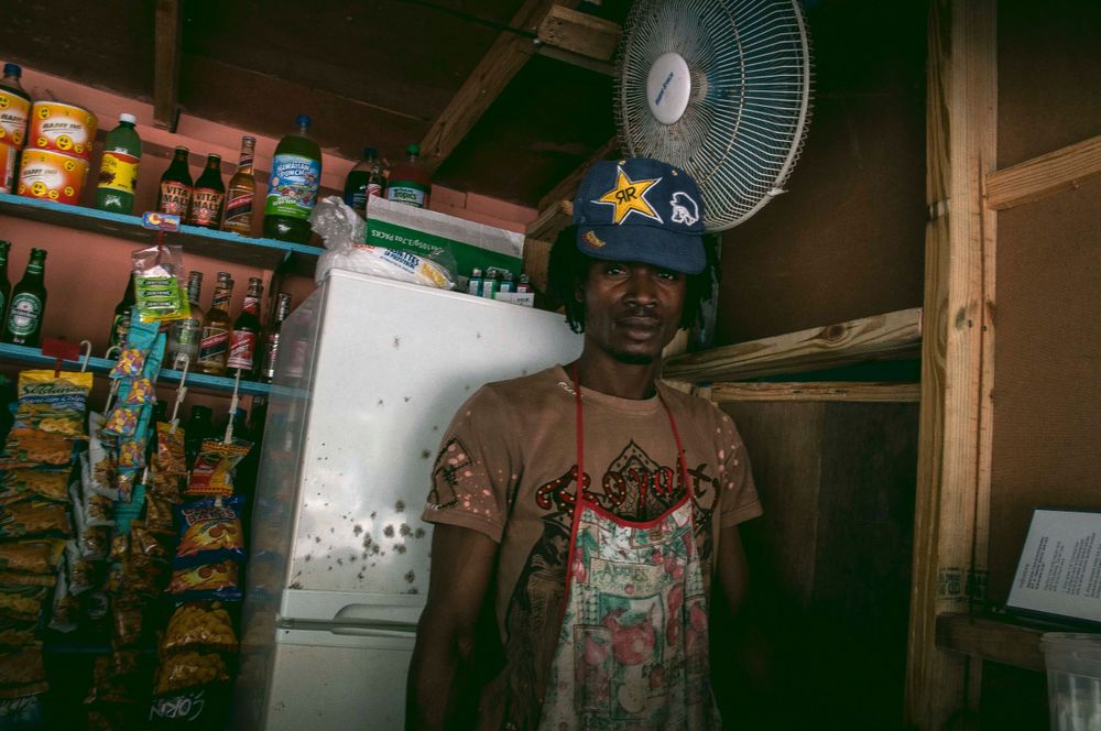 Small store interior with shelves of products and electric fan.