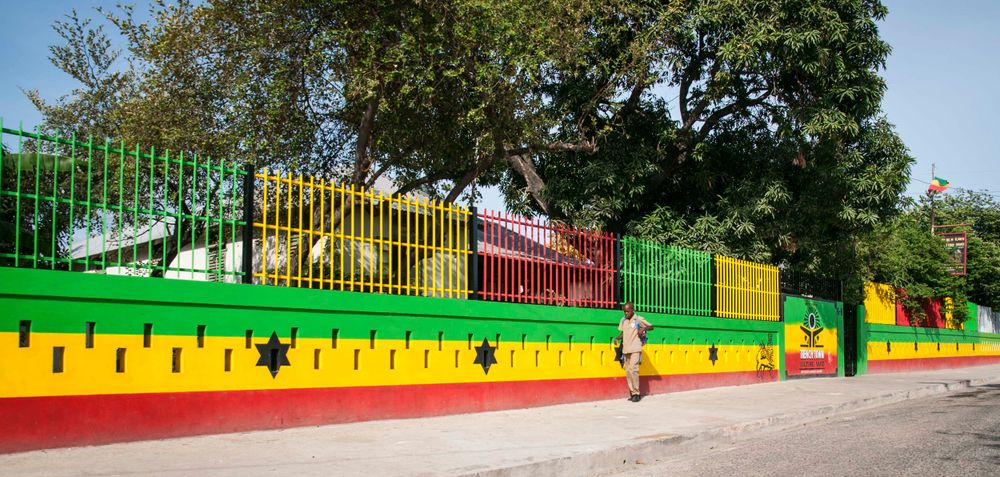 Colorful painted fence with green, yellow and red stripes stretches along an outdoor area.