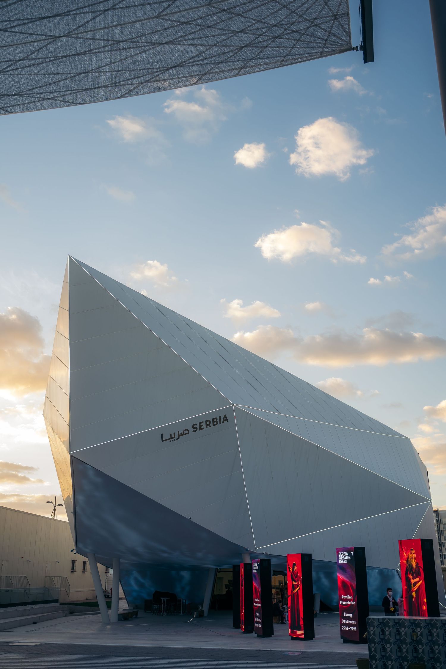 Modern angular Serbia pavilion building with geometric white facade at Expo 2020 Dubai at sunset.