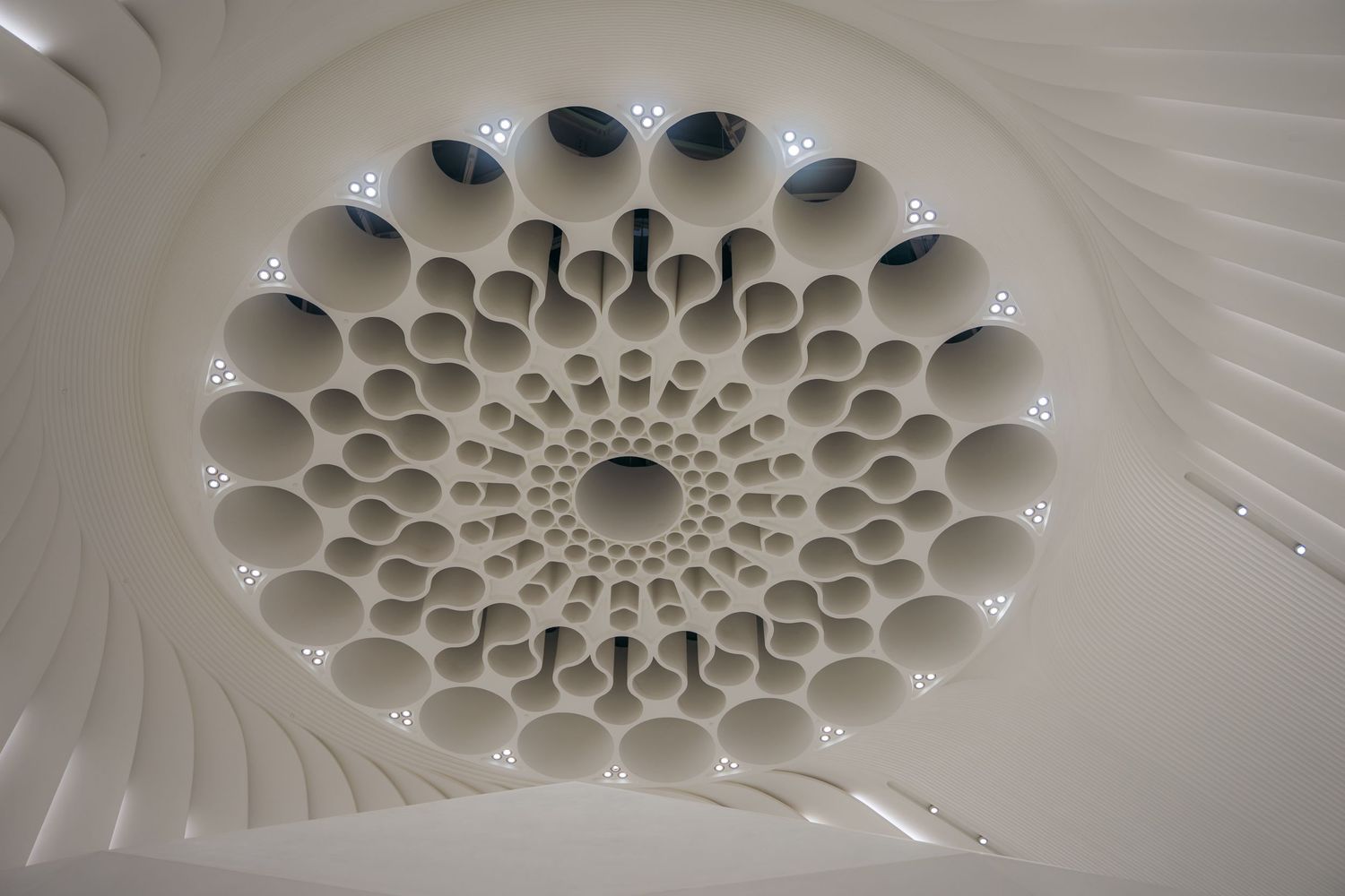 Stunning white architectural ceiling with fractal spiral pattern of cylindrical tubes and LED lights.