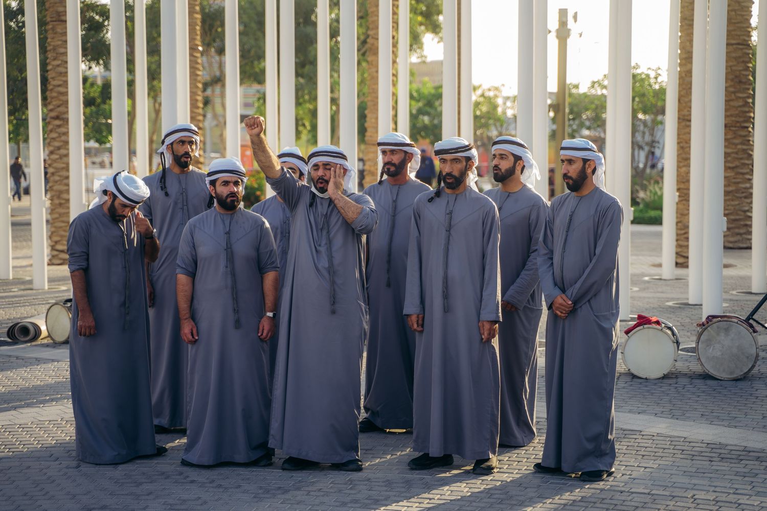Group of Emirati men in traditional gray kandura and white ghutras gathered outdoors in Dubai.