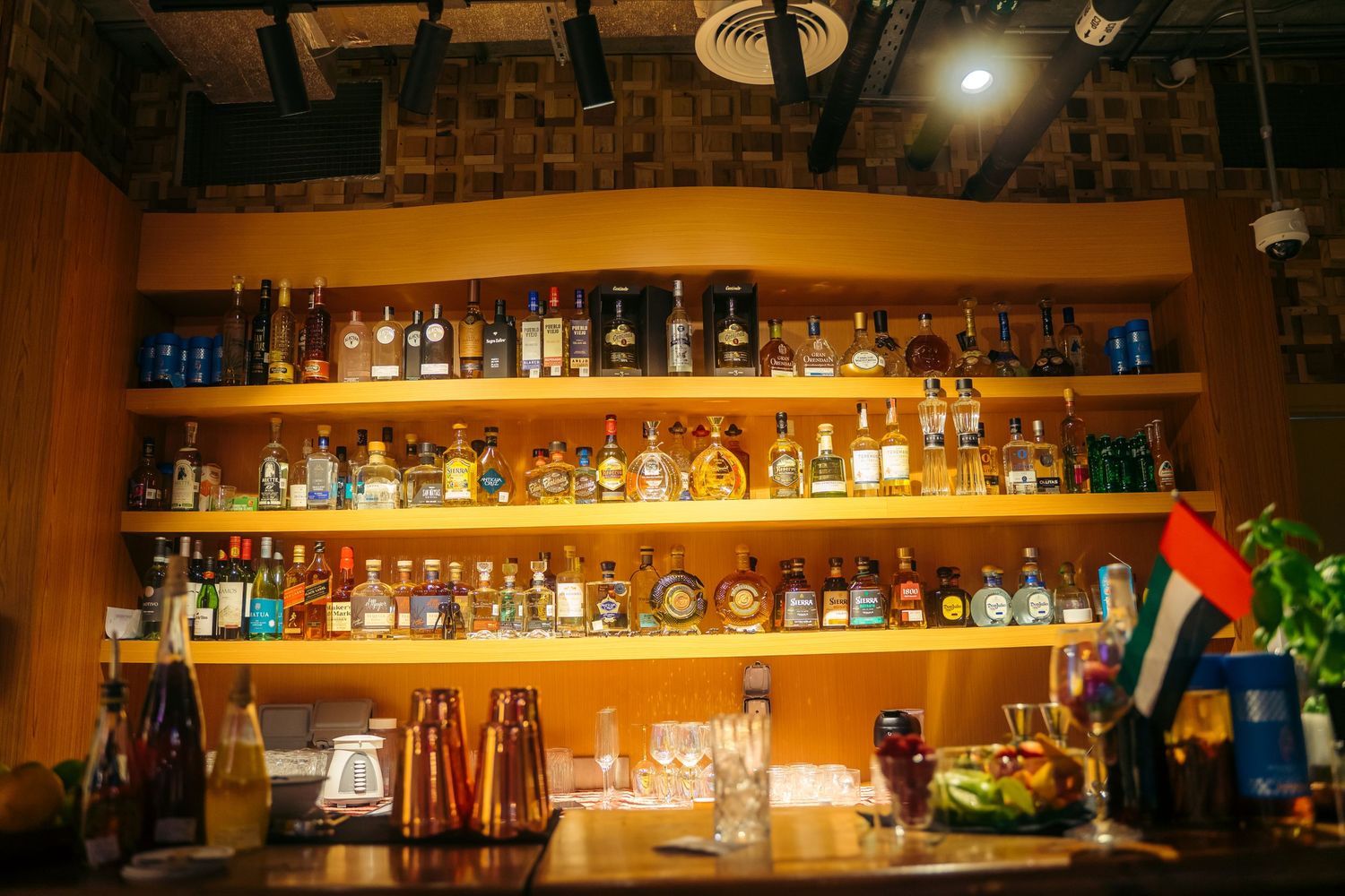Well-stocked bar shelves with liquor bottles and UAE flag at a Dubai restaurant.