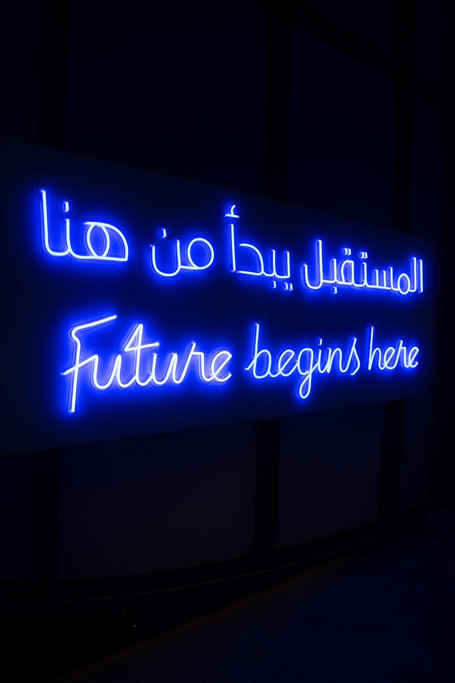 Blue neon sign reading Future Begins Here in English and Arabic in Dubai.