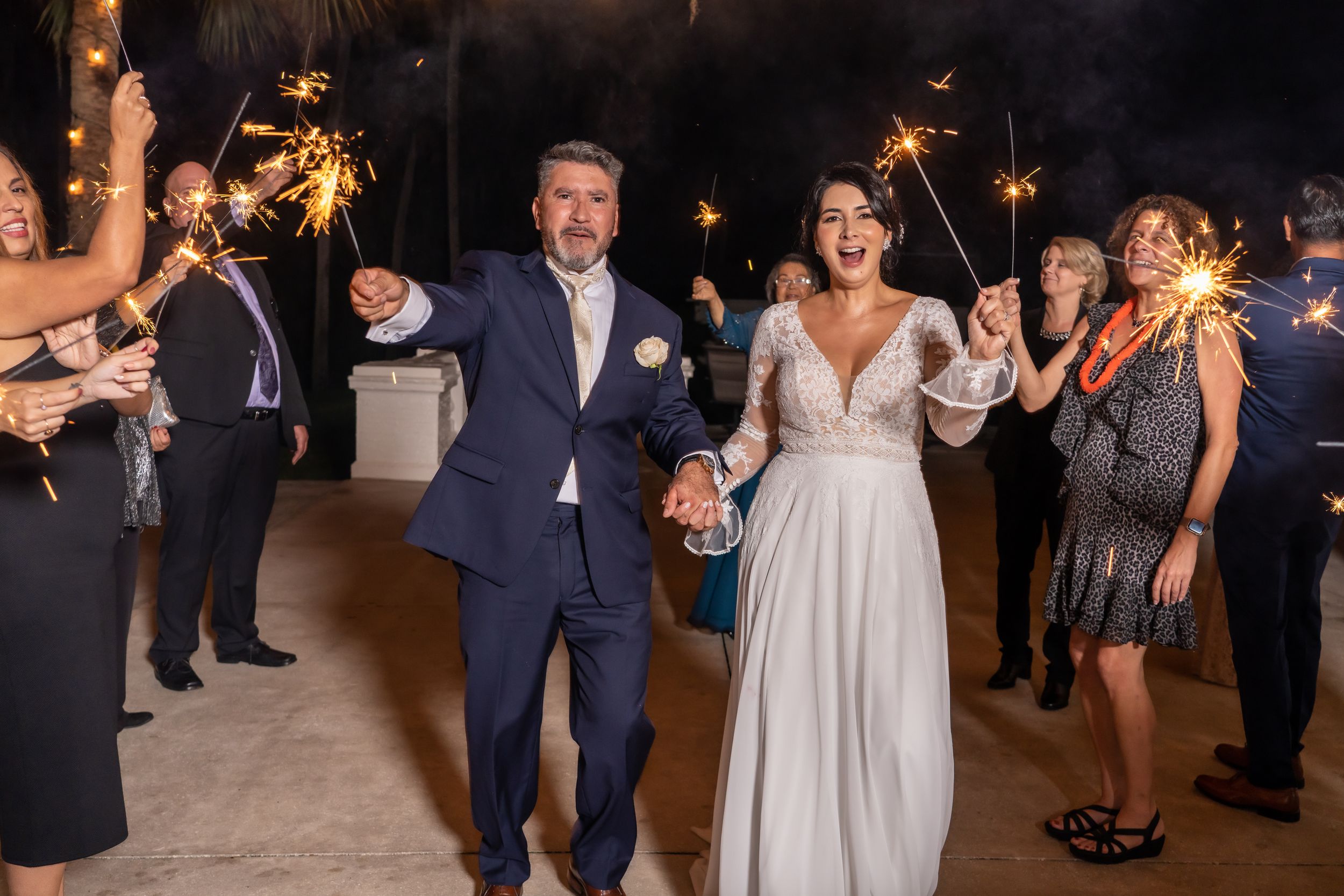 A couple celebrates on the dance floor surrounded by guests at their wedding reception.