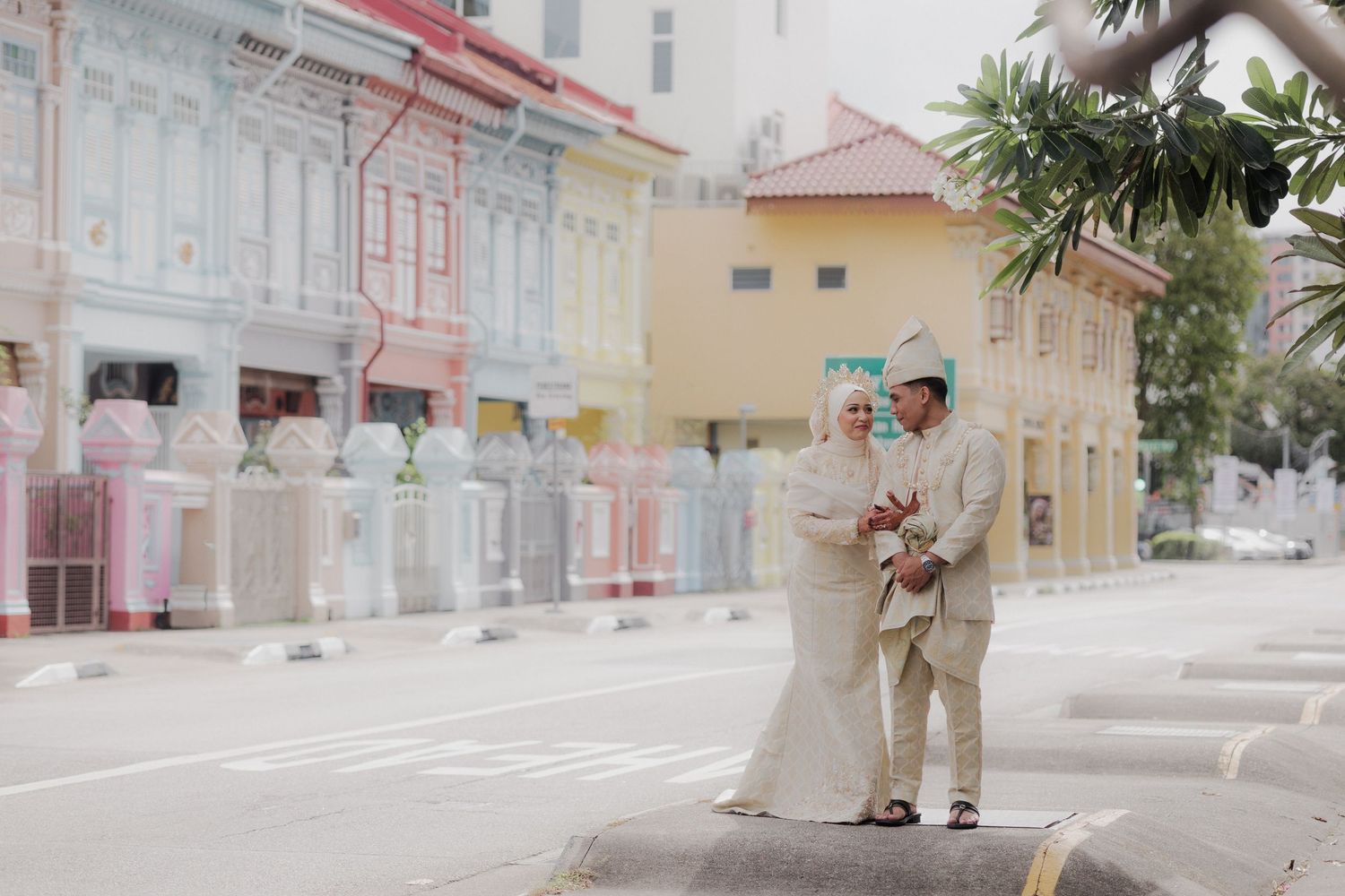 Couple posing playfully against colorful heritage shophouses with ornate details.