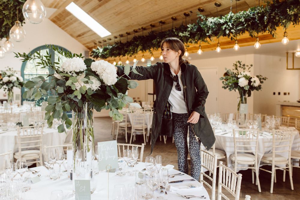 Wedding venue interior with vaulted wooden ceiling, string lights, and white table settings.