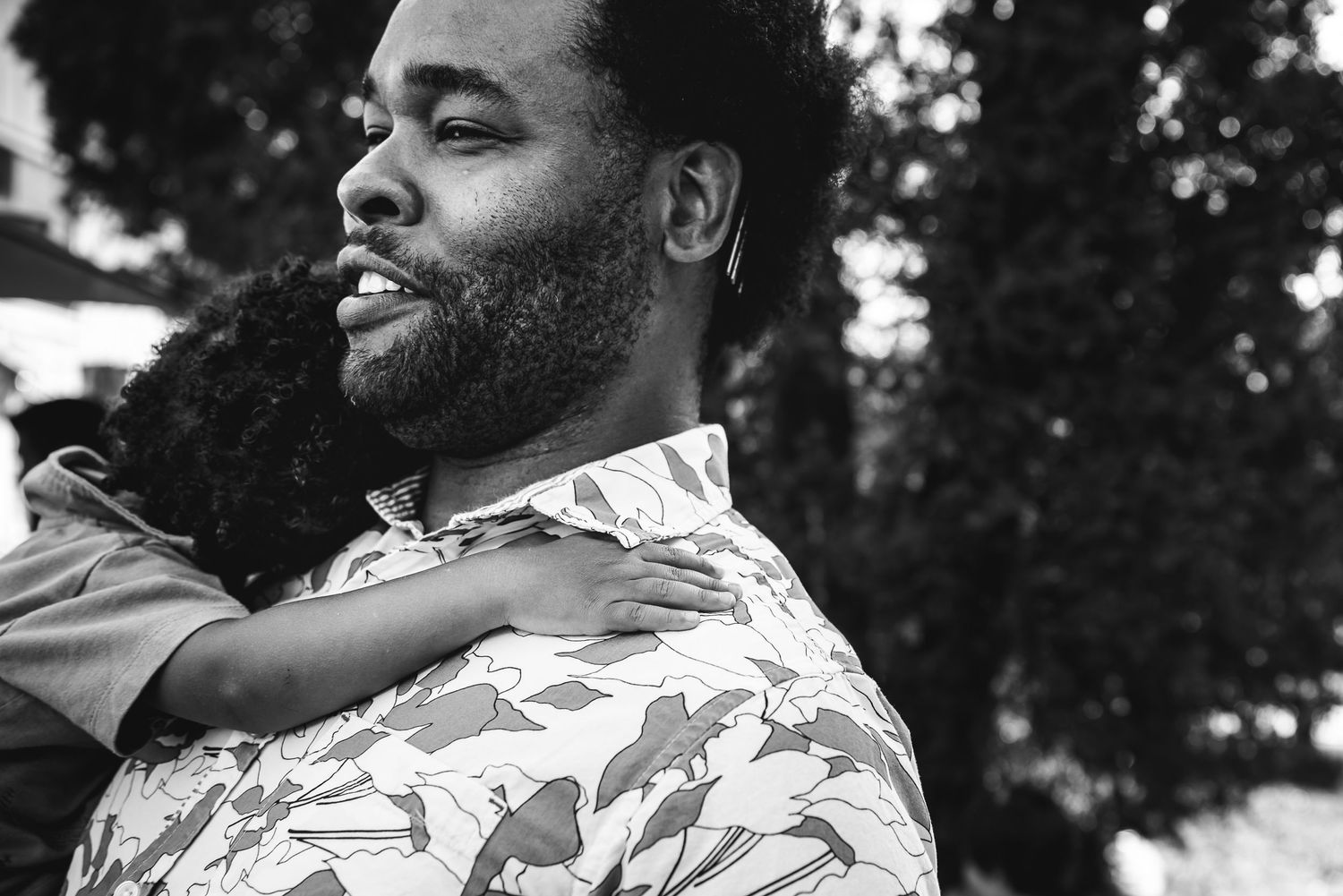 Close up on a man holding his son, who's holding on with his little hand.